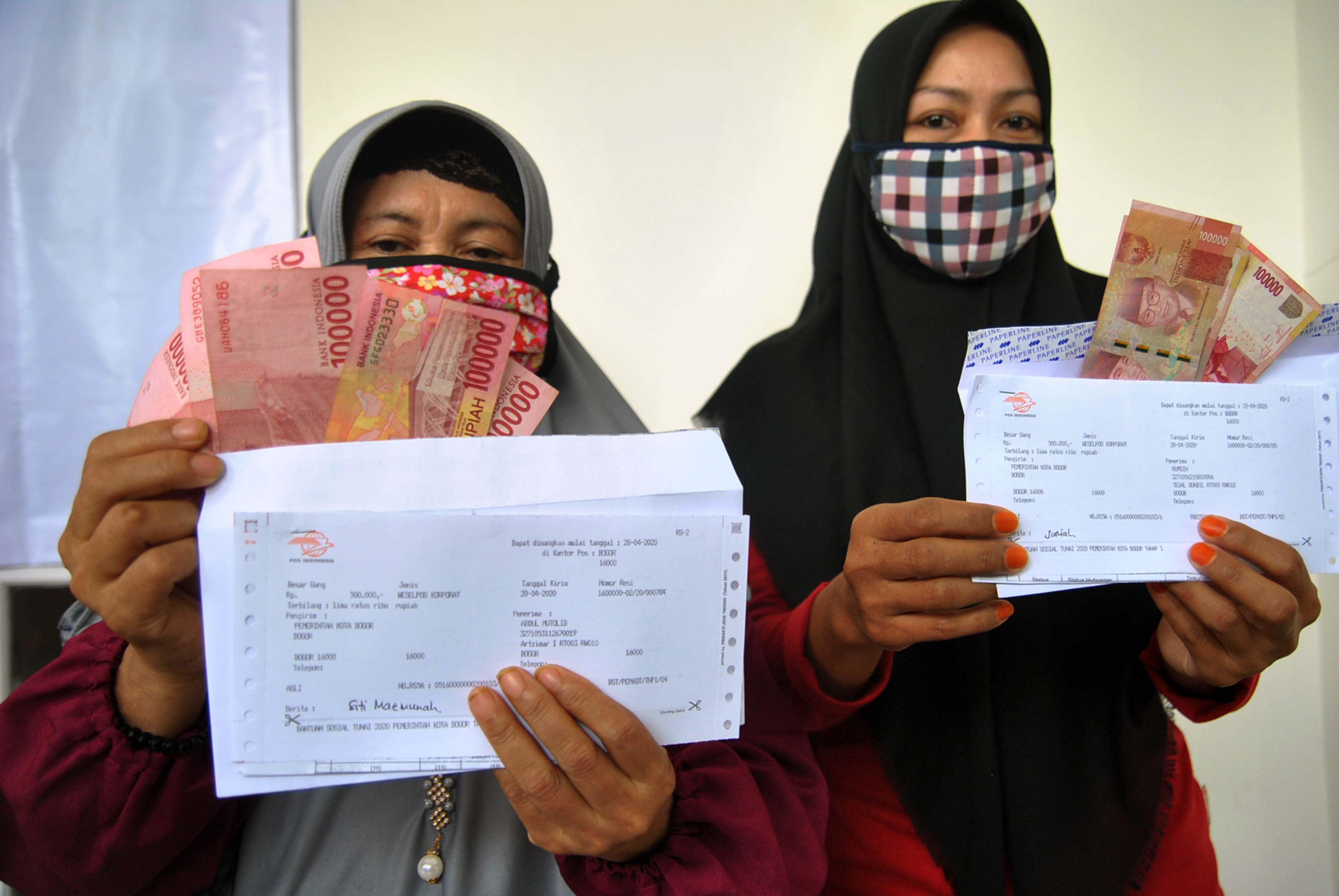 Warga penerima bantuan menunjukkan uang tunai saat pembagian Bantuan Sosial Tunai Non Data Terpadu Kesejahteraan Sosial (DTKS) di Bogor.