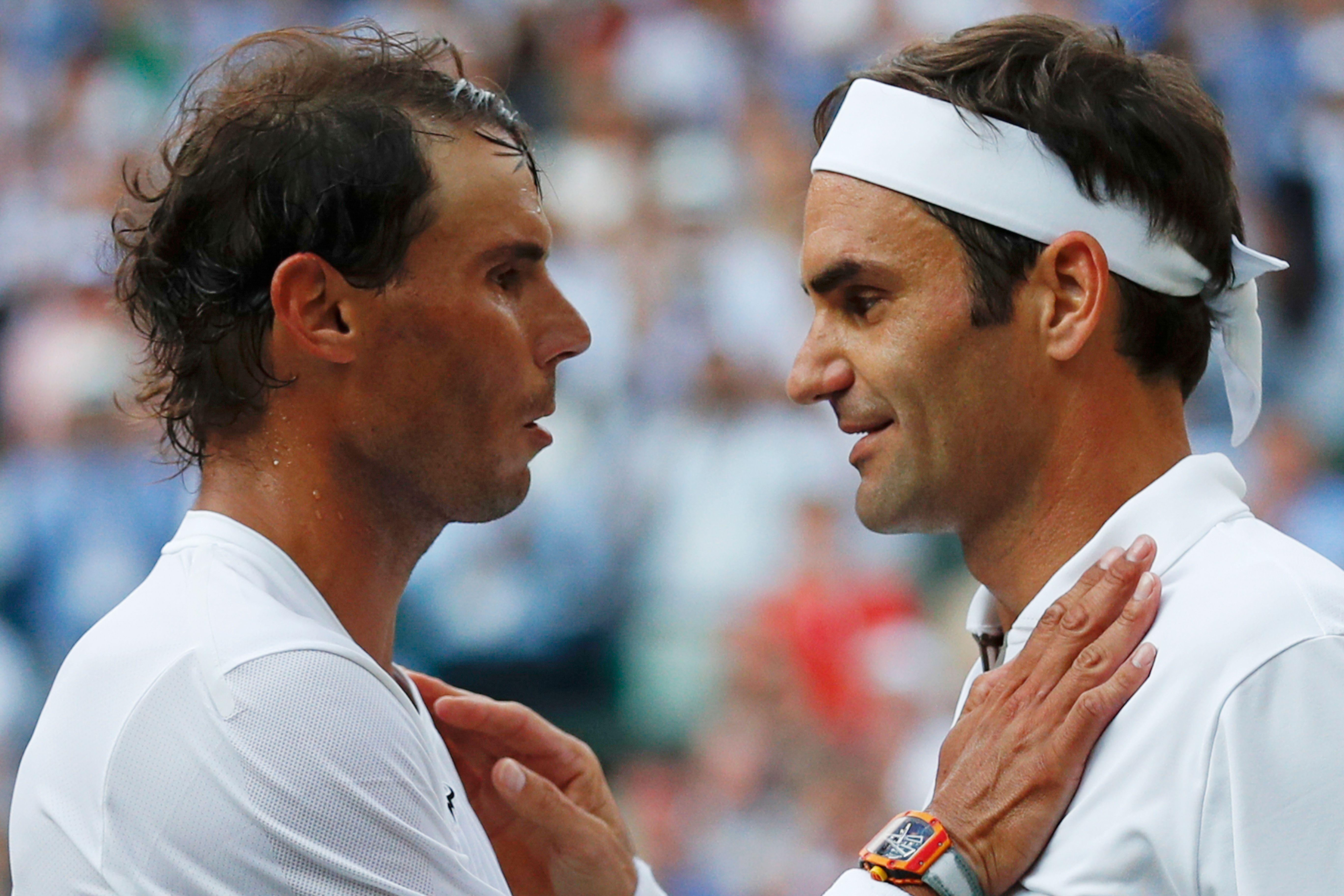 Petenis Spanyol Rafael Nadal (kiri) dan petenis Swiss Roger Federer bersalaman usai semifinal grand slam Wimbledon 2019, 12 Juli tahun lalu.
