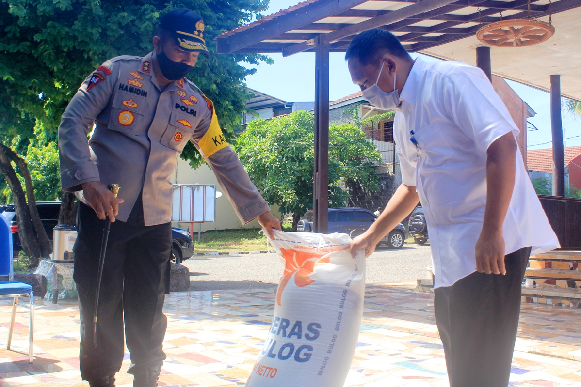 Pemimpin Wilayah Perum Bulog NTT Taufan Akib (kanan) menyerahkan beras untuk dapur umum Polda NTT kepada Kapolda NTT Irjen Hamidin.