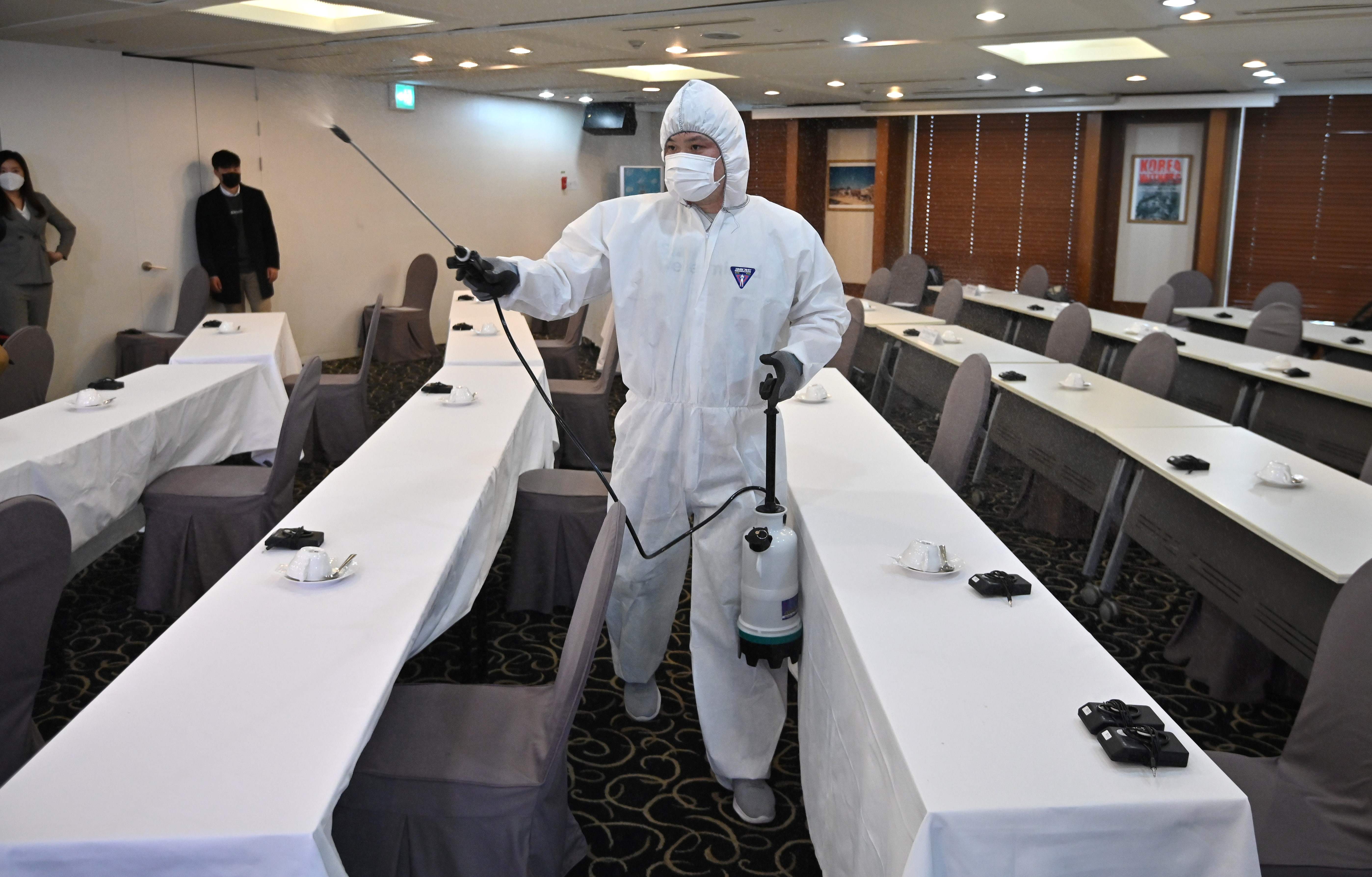 Pekerja menyemprotkan cairan disinfektan di ruang konferensi pers yang akan digunakan Perdana Menteri Korsel Chung Se-kyun.