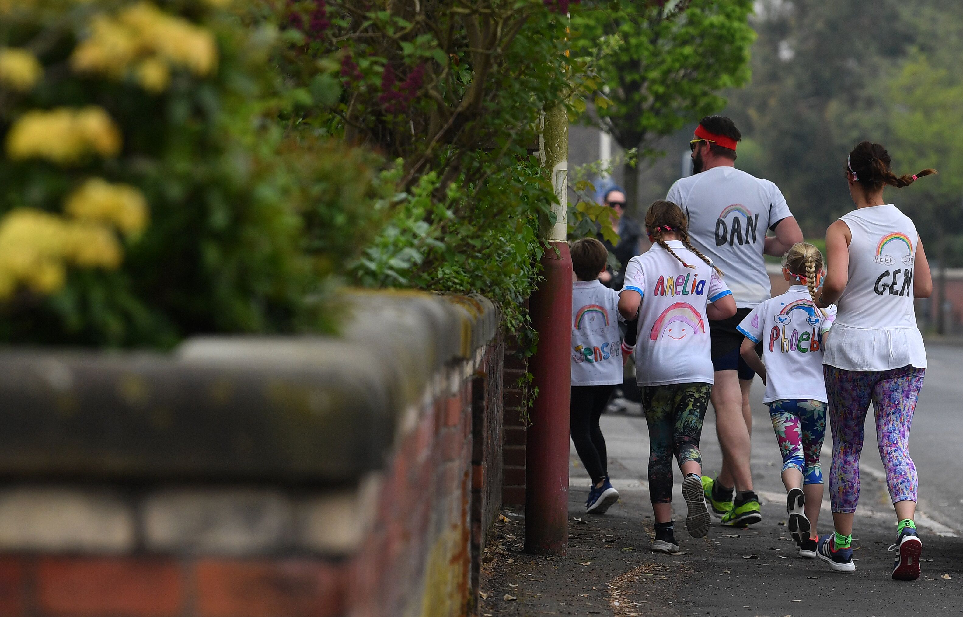 Sebuah keluarga yang mengenakan kaos bergambar pelangi yang dijadikan simbol harapan selama pandemi covid-19 berlari di Southport, Inggris.