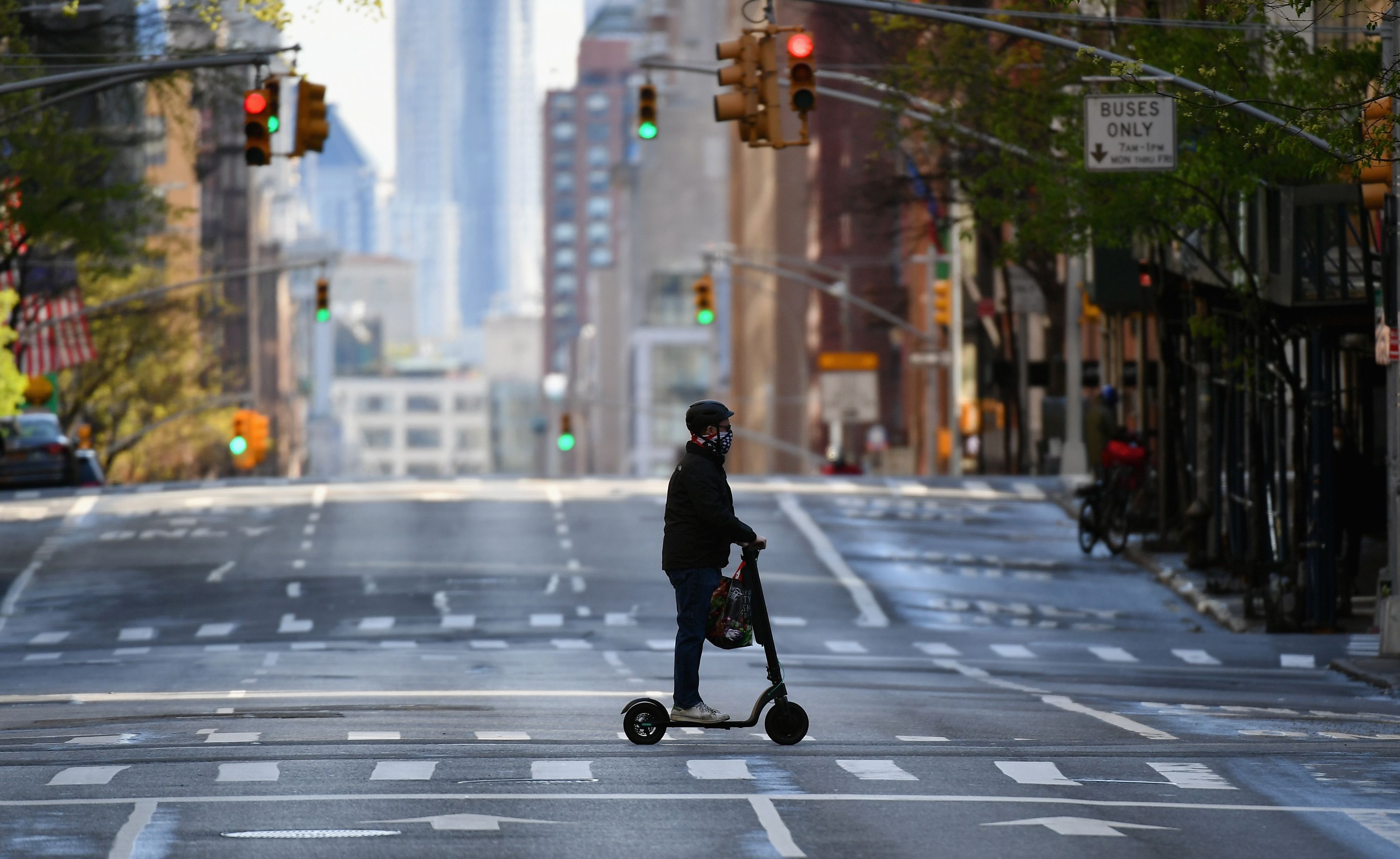 Seorang warga melintas menggunakan skuter di jalan Kota New York, Amerika Serikat yang kosong.