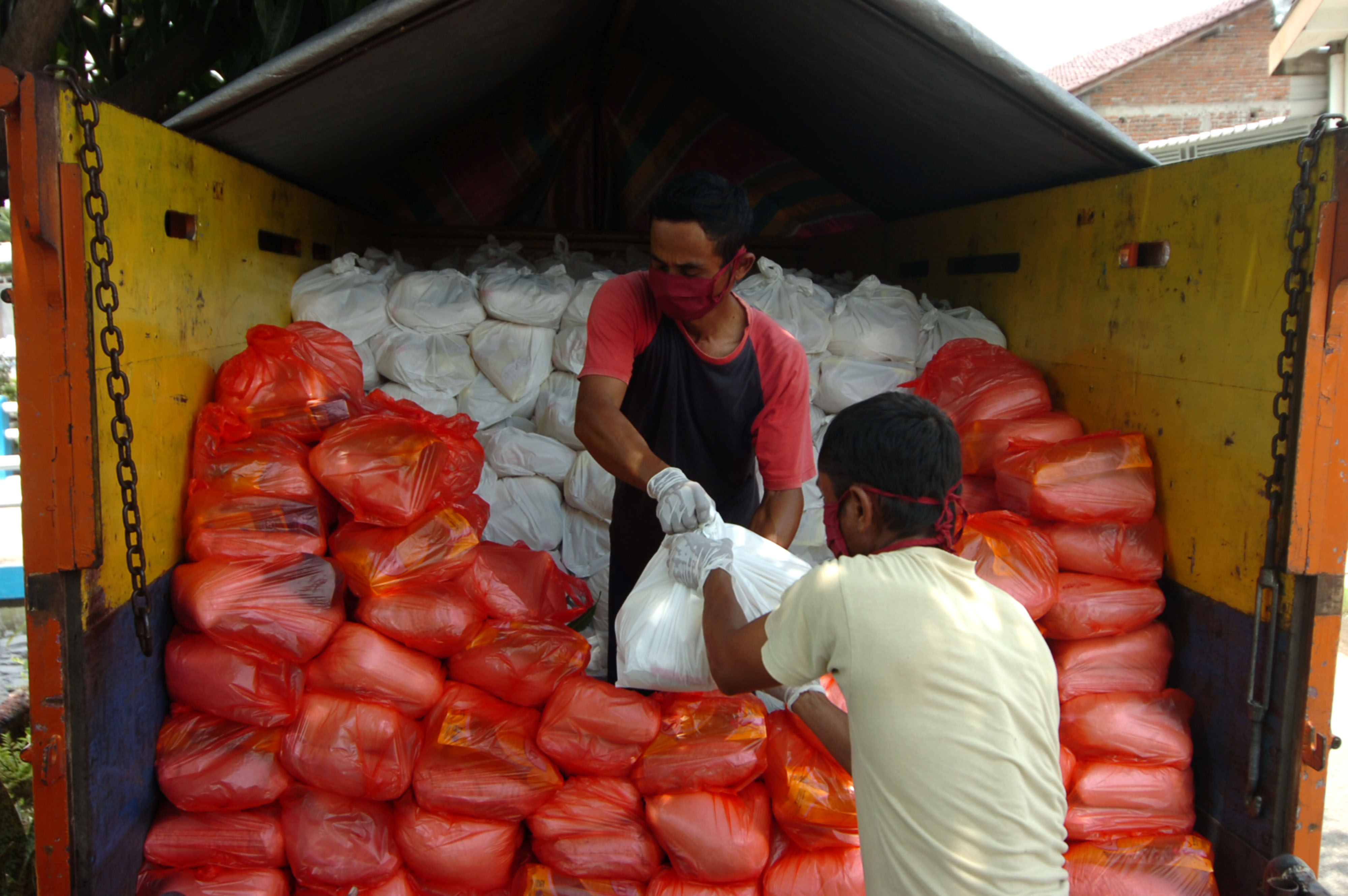 Pekerja memindahkan paket sembako untuk didistribusikan ke Kelurahan, RW dan RT di Kantor Kecamatan Pesurungan Kidul, Tegal, Jawa Tengah.