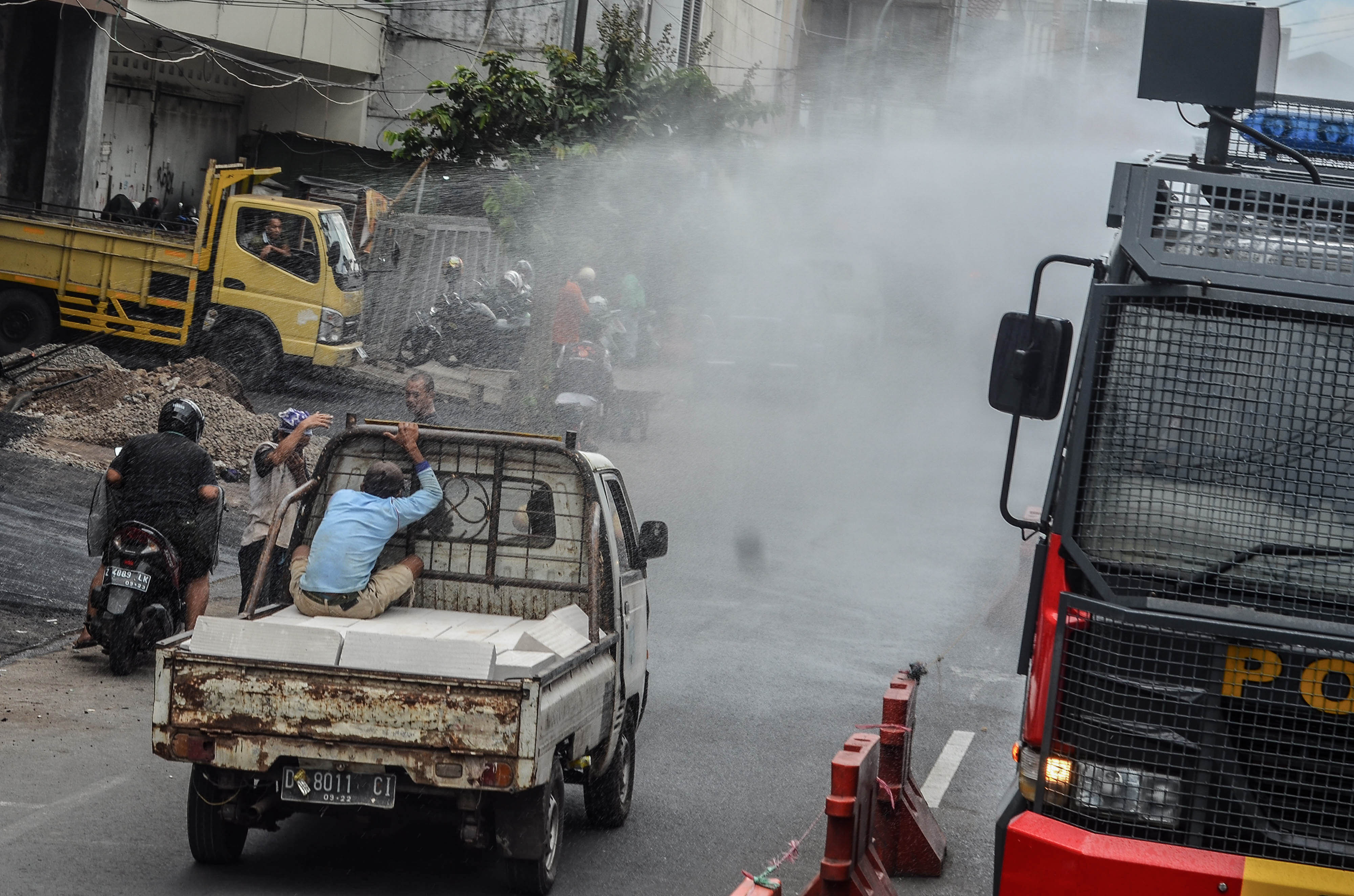  Petugas kepolisian menyemprotkan disinfektan menggunakan mobil armor water canon Polres Tasikmalaya Kota di Kota Tasikmalaya, Jawa Barat.