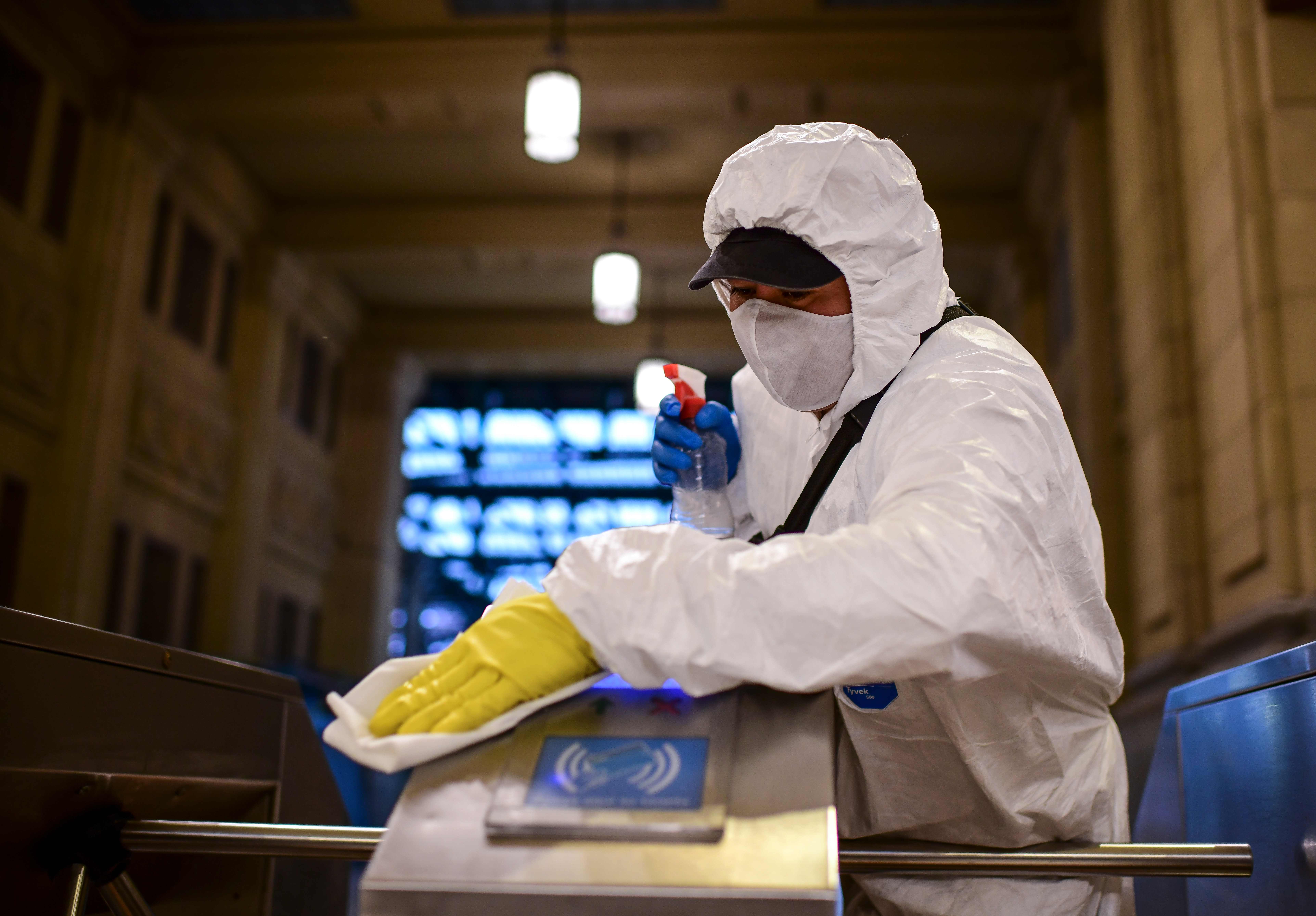 Petugas menyemprotkan disinfektan di gerbang stasiun kereta di Buenos Aires, Argentina.