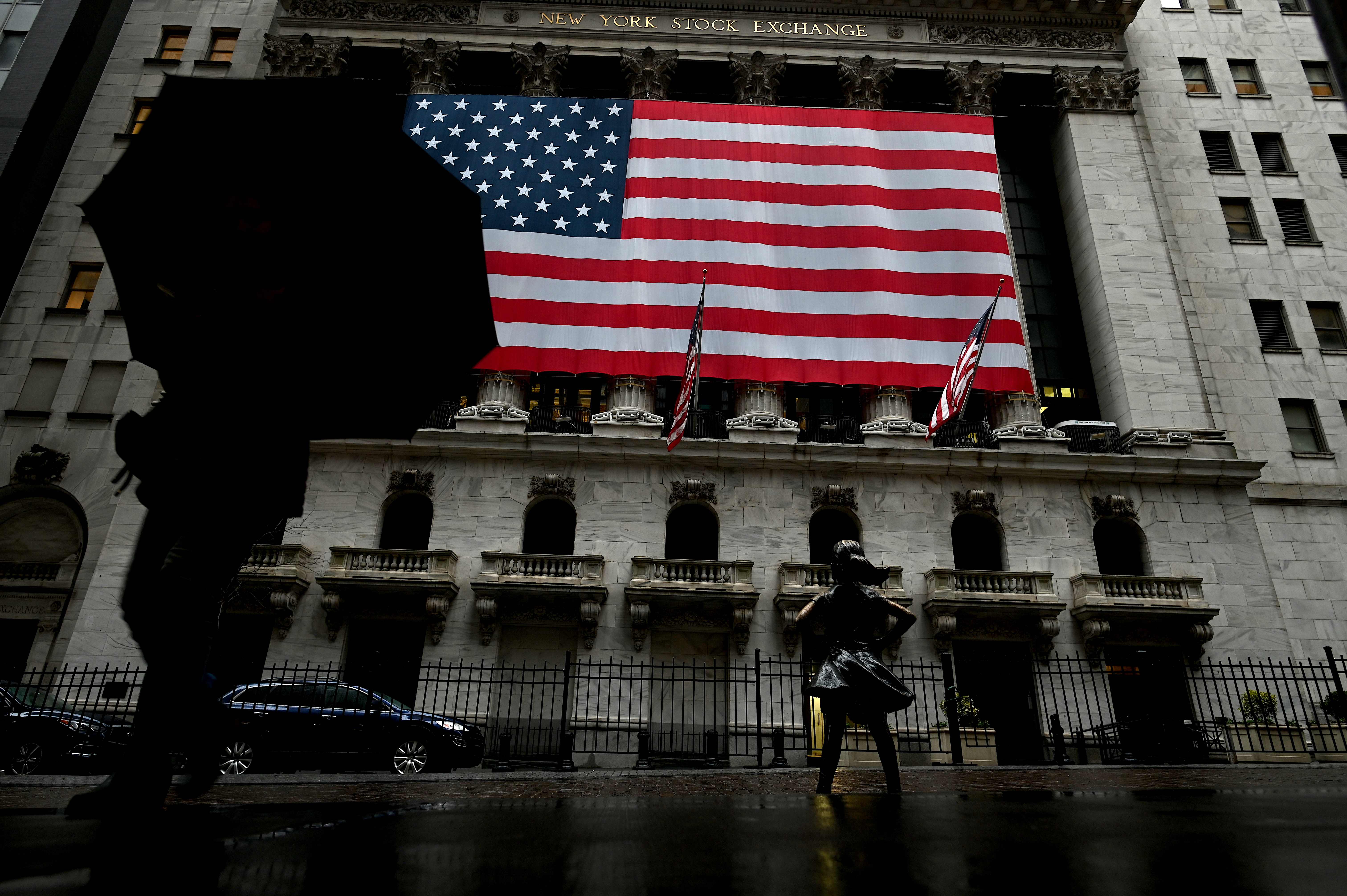 Sejumlah orang melintas di depan gedung Bursa Saham New York Wall Street. Saham -saham  dibuka sedikit menguat, Jumat (17/4/2020).