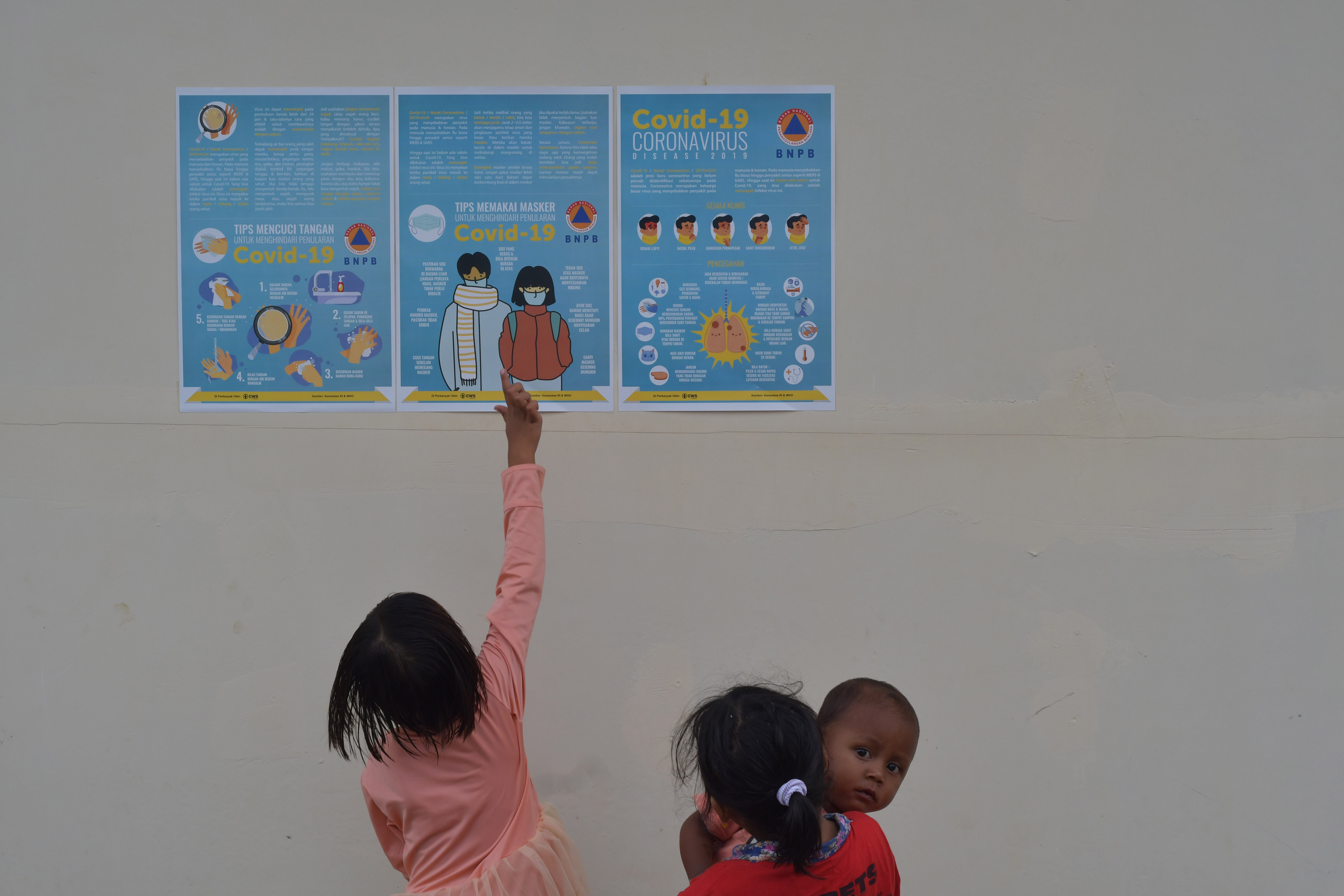 Anak-anak membaca poster berisi pengenalan Covid-19 di dinding hunian sementara warga korban Gempa dan Tsunami, Palu, Sulteng, Senin (6/4).