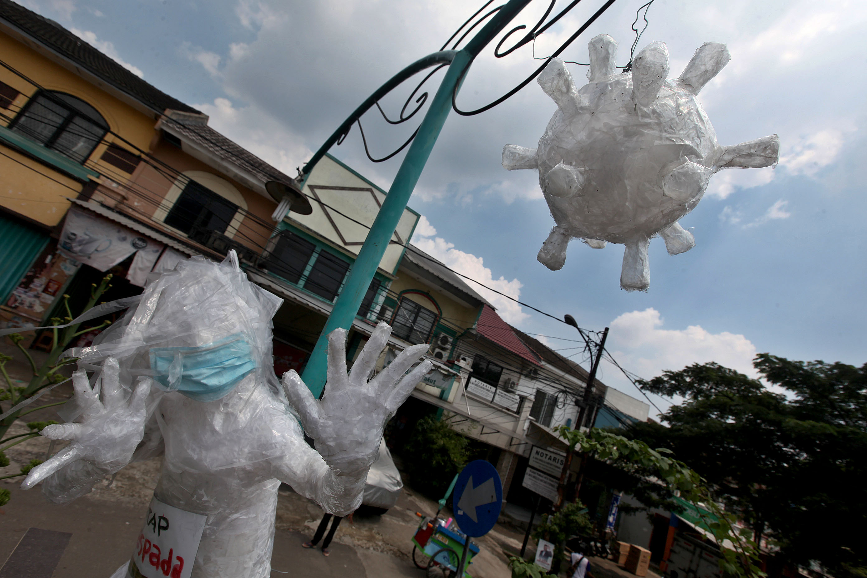 Warga memasang patung antikorona di depan pintu masuk perumahan di Pamulang, Tangerang Selatan, Banten, Minggu (12/4).