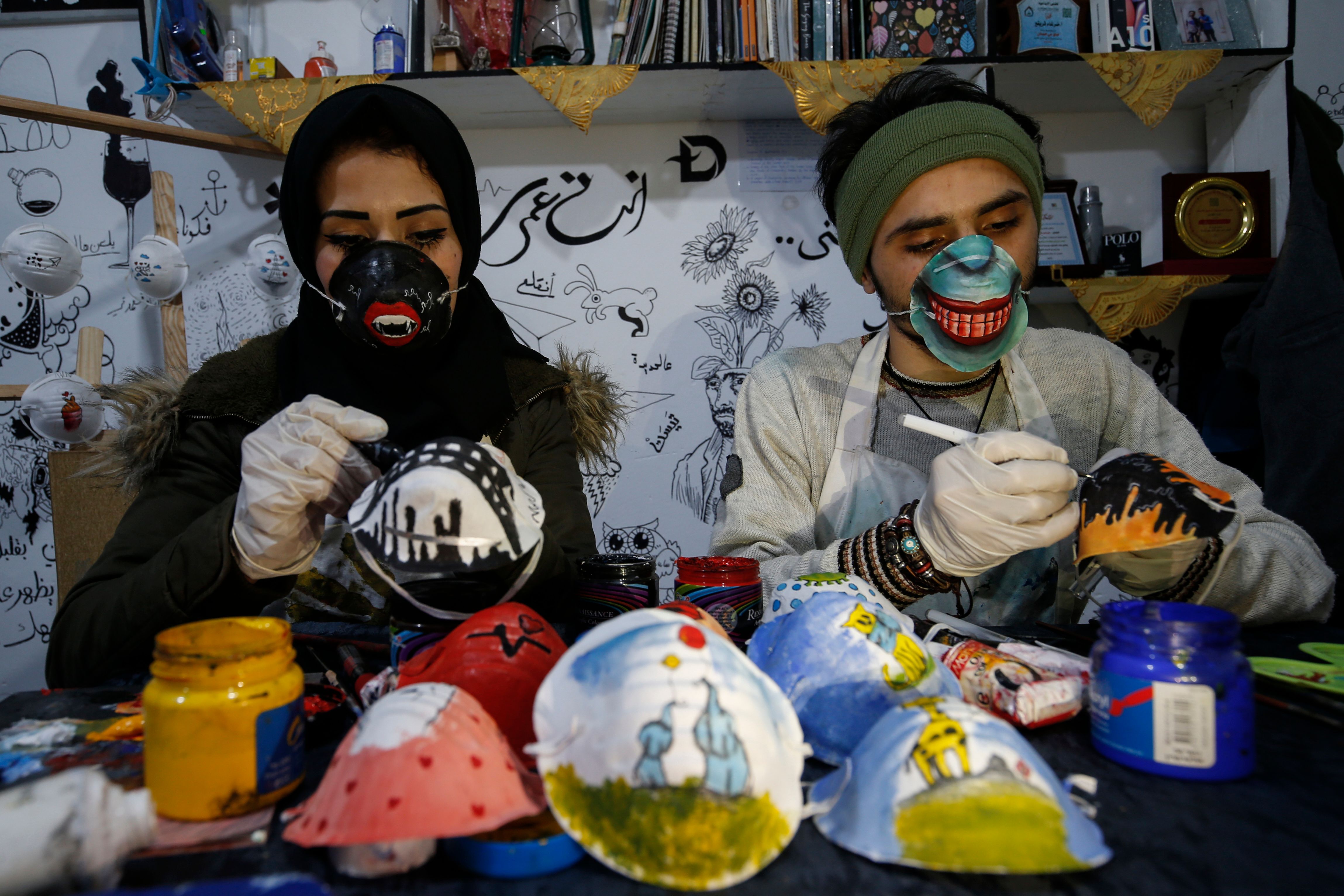 Seniman Palestina Samah Said dan Dorgham Krakeh sedang melukis masker N95 untuk proyek peningkatan kesadaran terhadap covid-19 di Gaza
