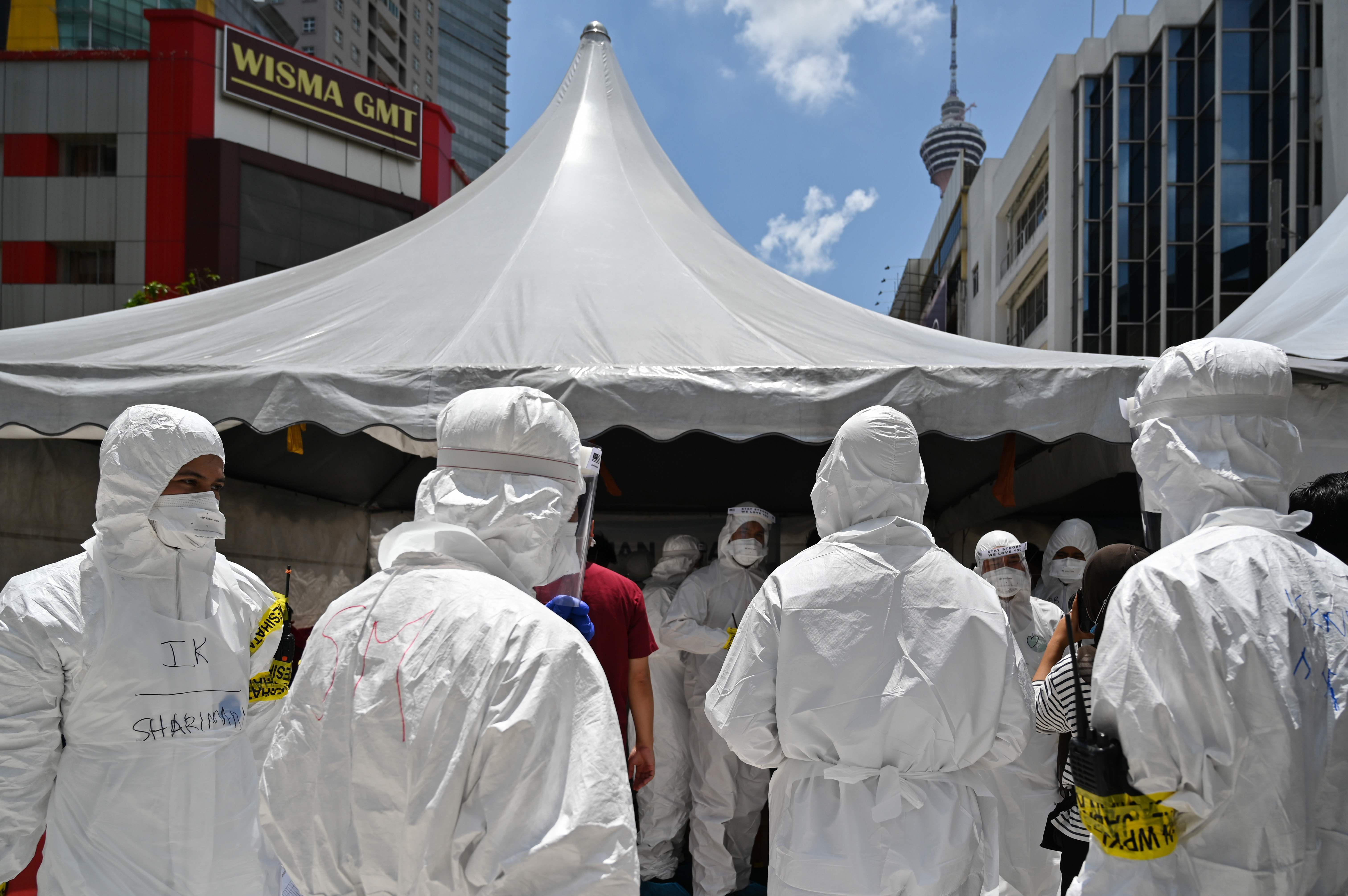 Petugas kesehatan mengenakan APD bersiap memasuki sebuah gedung apartemen di Kualu Lumpur yang menjadi pusat penyebaran covid-19.