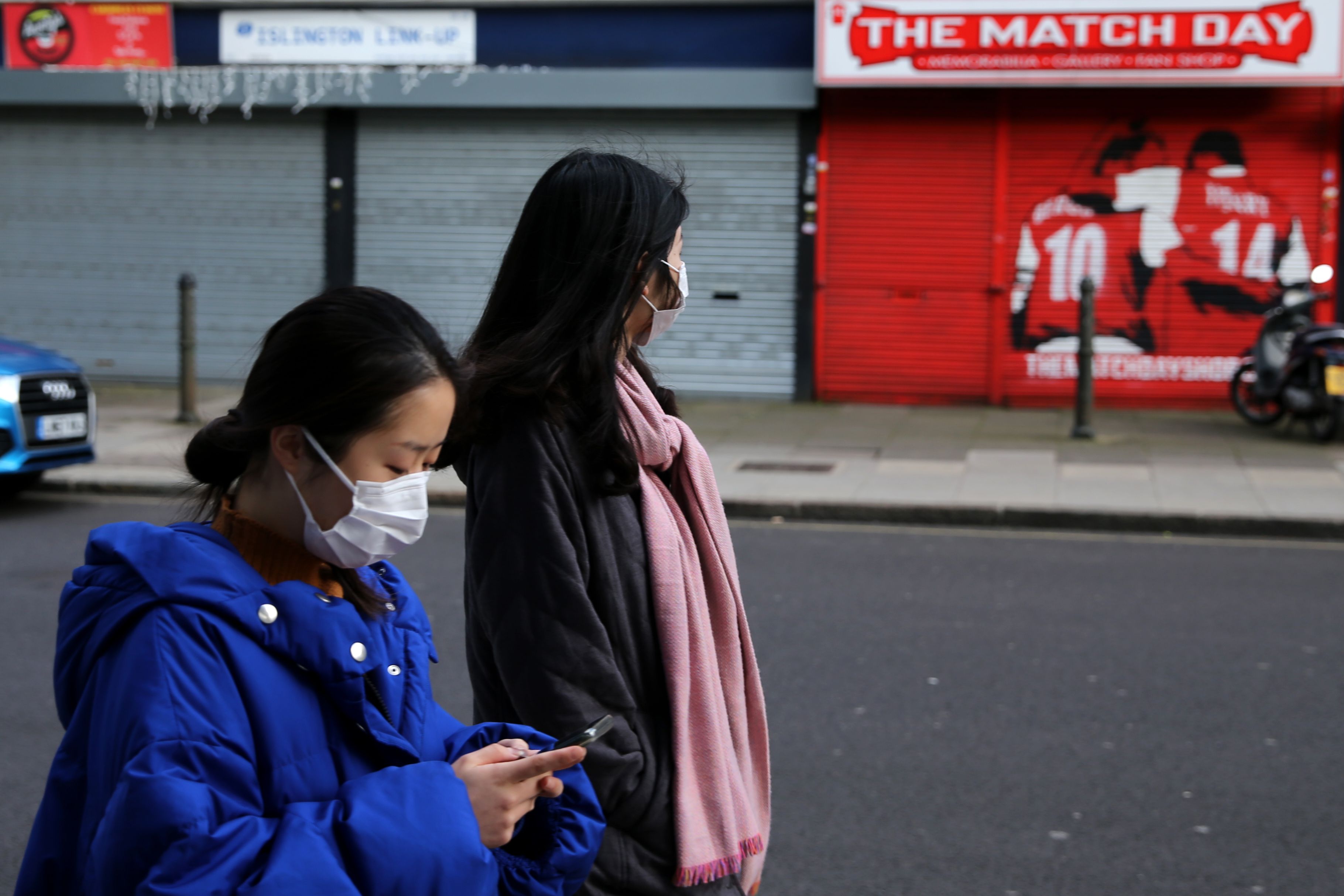 Warga menggunakan masker berjalan di sekitar stadiion Emirates milik Arsenal di London, Inggris