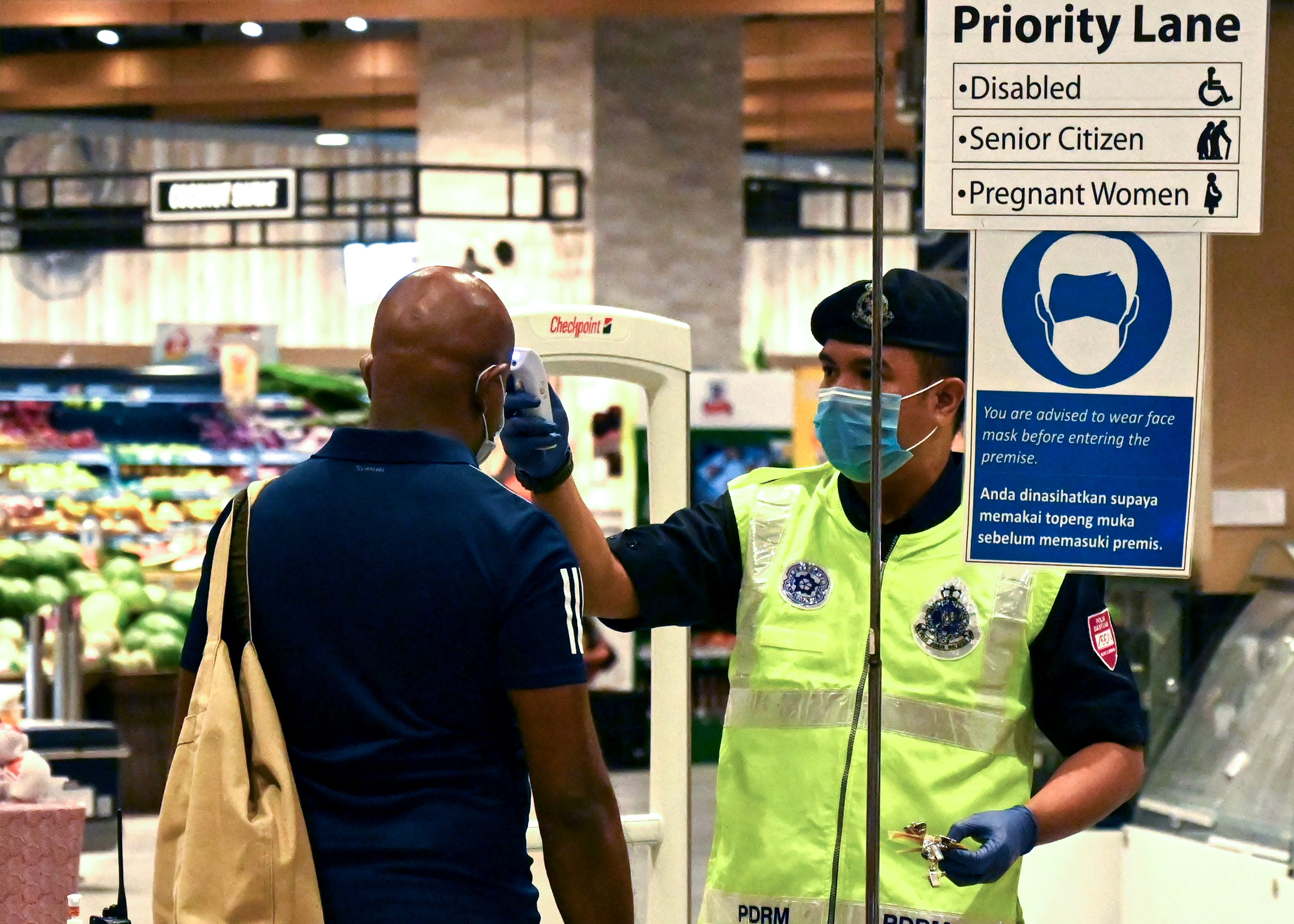 Polisi memeriksa suhu seorang pengunjung di supermarket di Penang, Malaysia, awal April lalu.