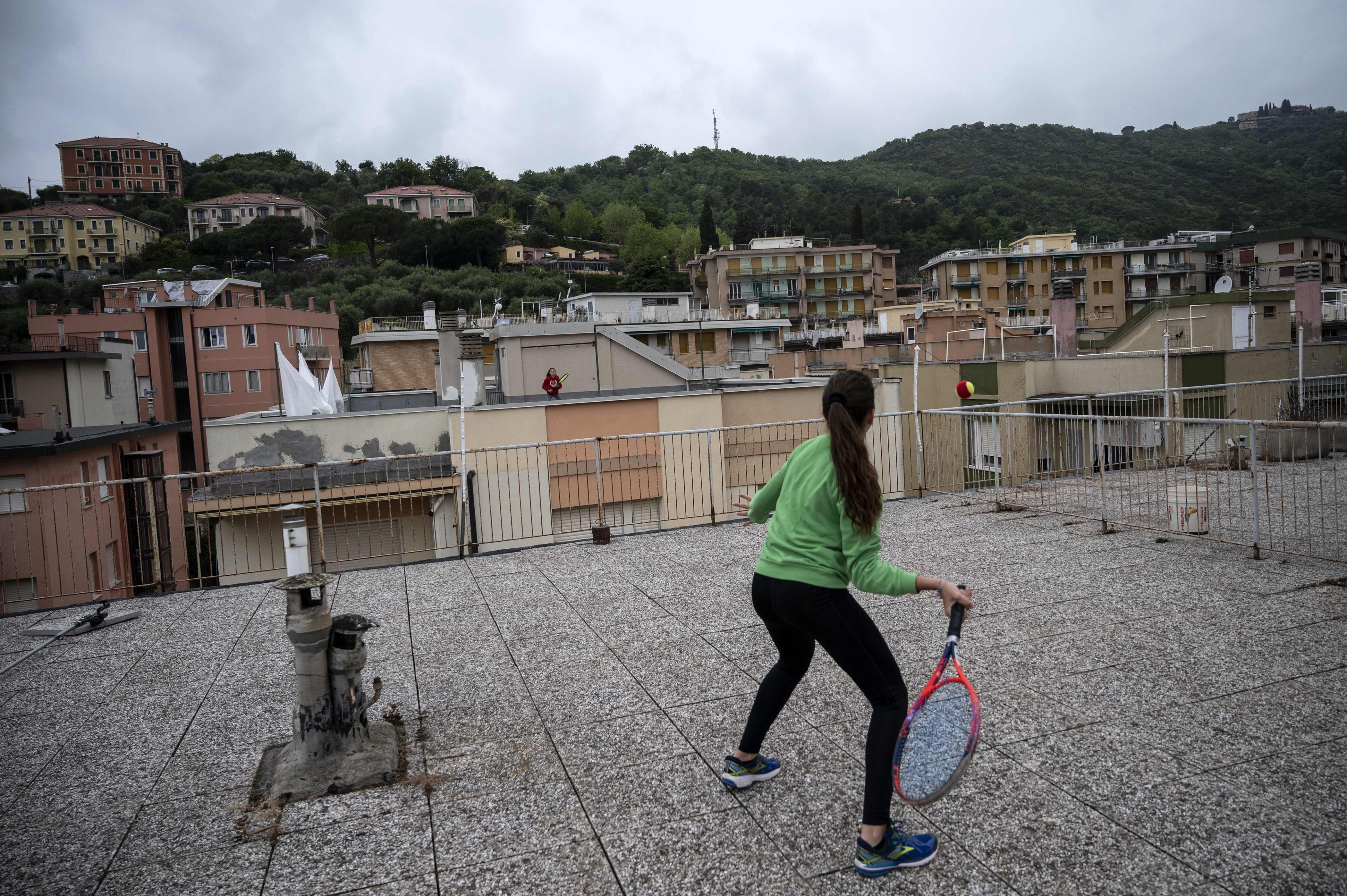  Vittoria Oliveri (depan) bermain tenis dengan Carola Pessina di latar belakang di atap rumah mereka Wilayah Liguria, Italia barat, Minggu.