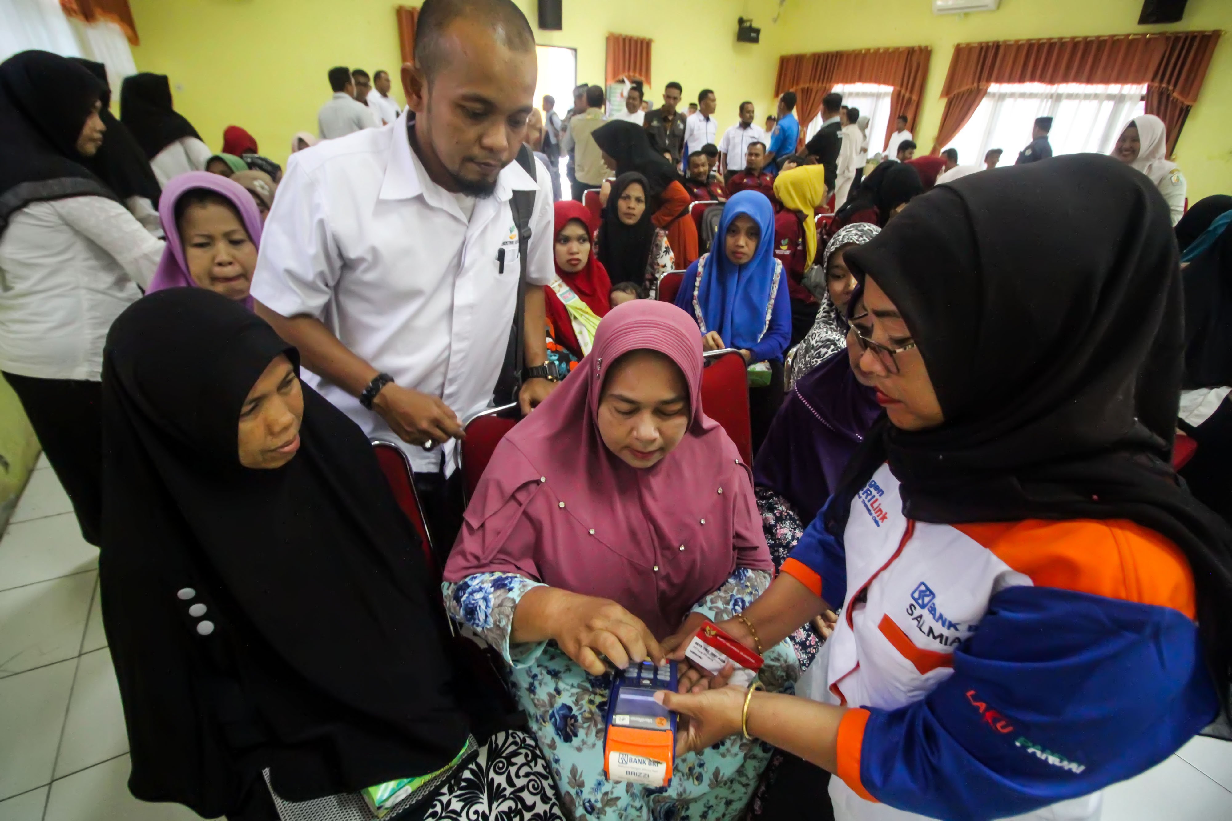 Para penerima bantuan program keluarga harapan sedang mengakses kartu keluarga sejahtera melalui mesin EDC.