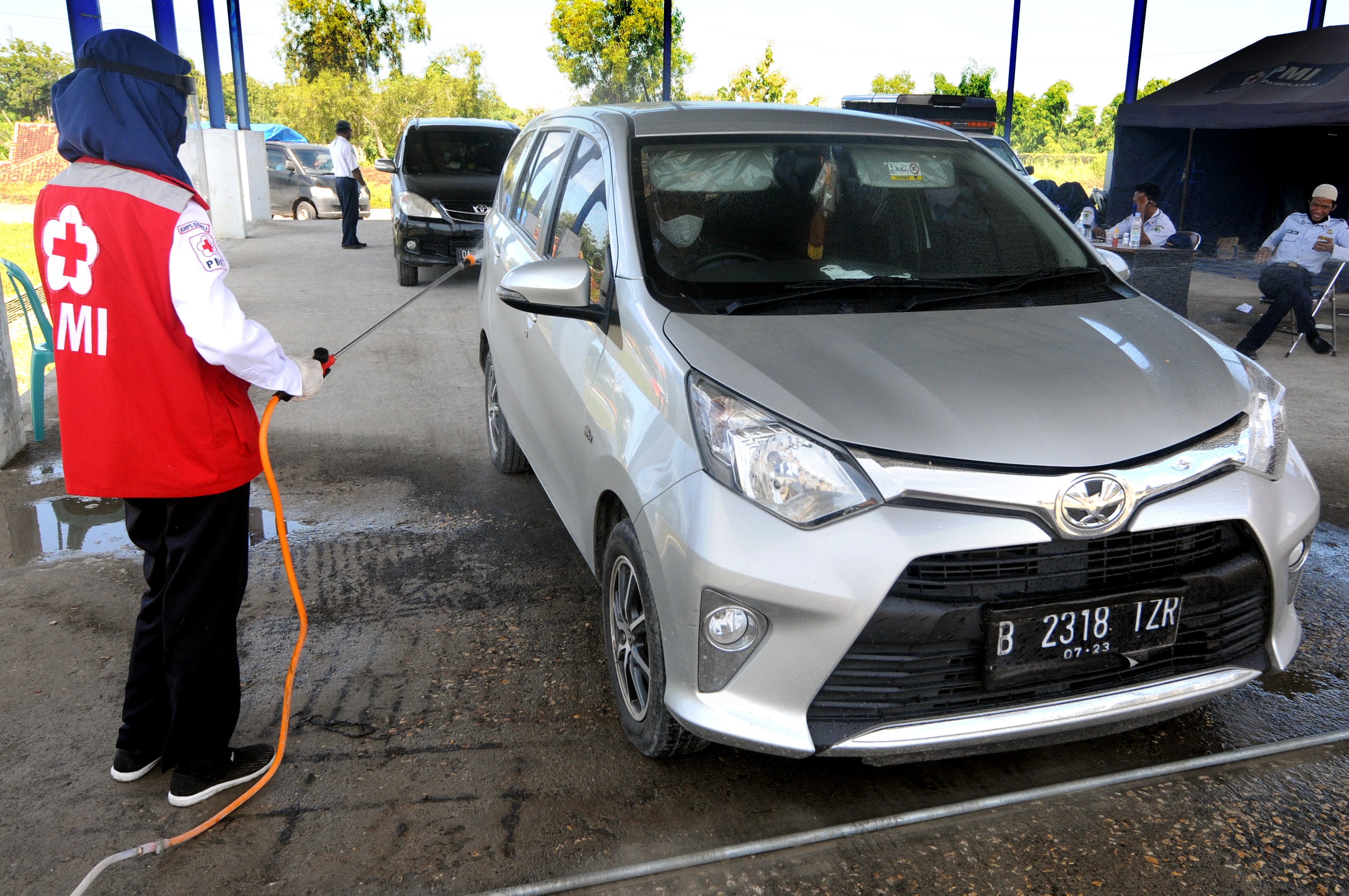 Petugas menyemprotkan disinfektan pada mobil pribadi di Pos Pantau Mudik di Terminal Cargo, Pamekasan, Jawa Timur.