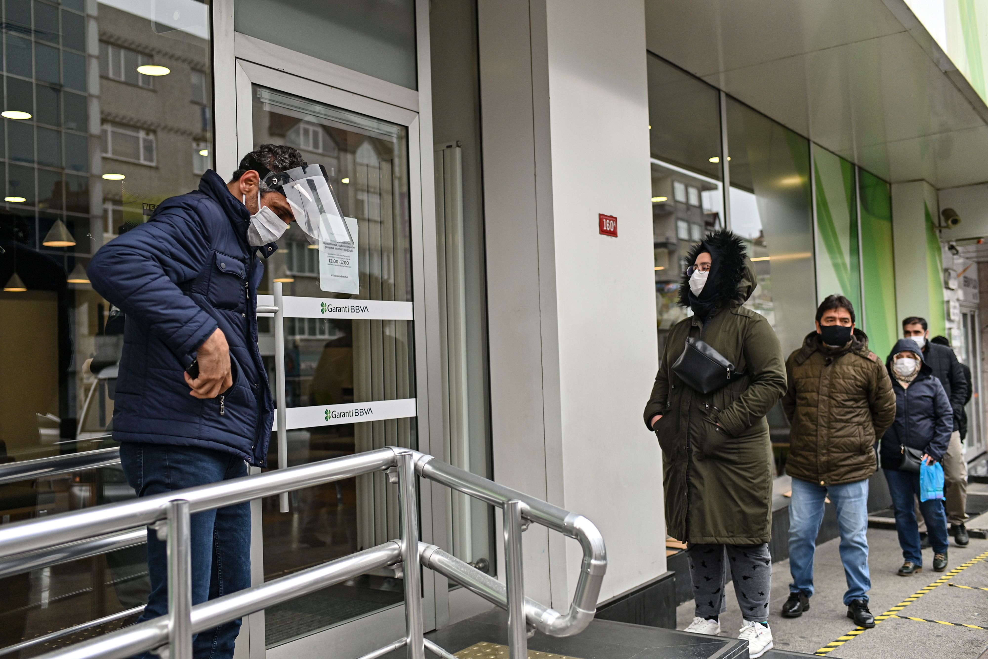 Warga mengantre masuk bank sembari tetap menjaga jarak sosial di Istanbul, Turki.