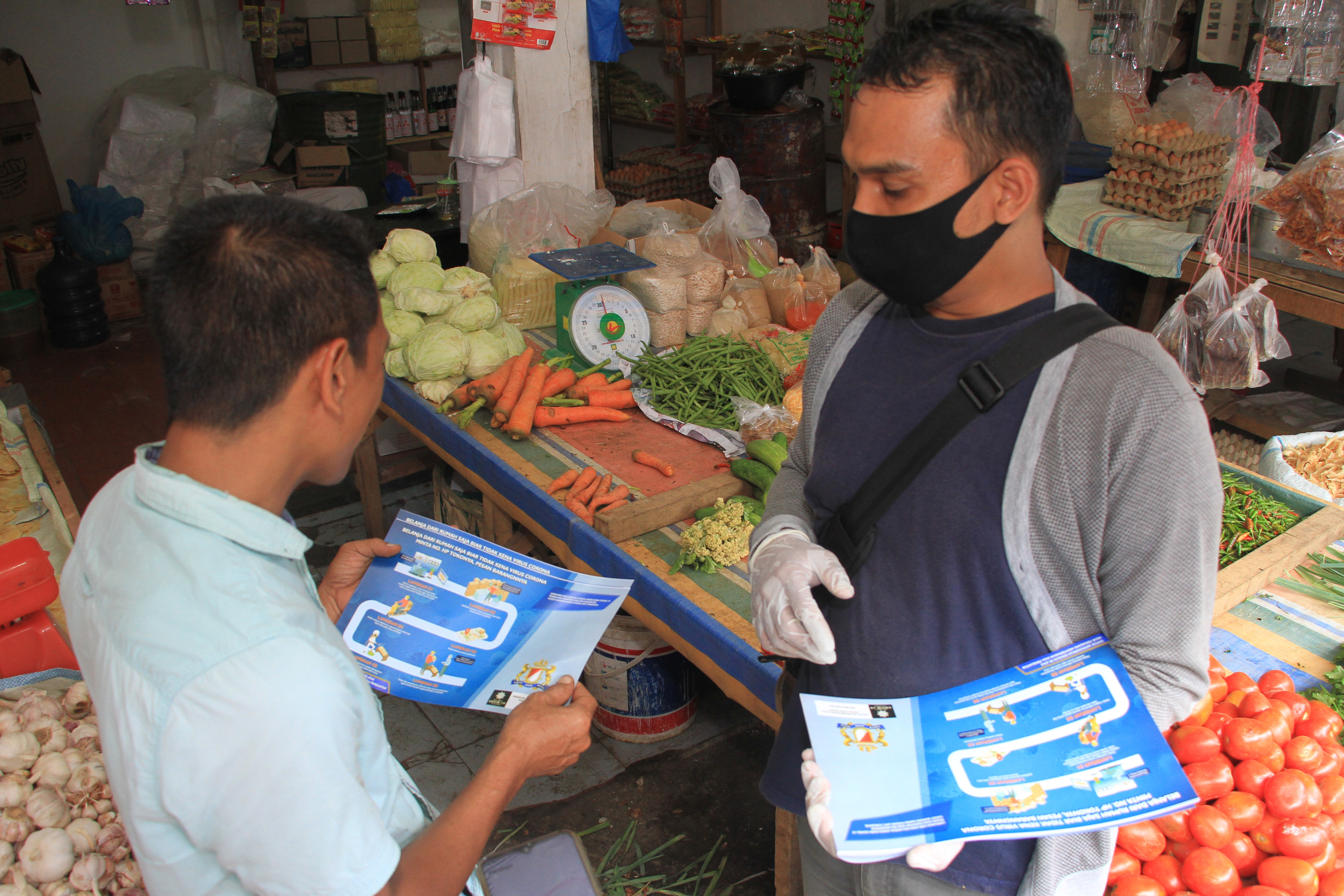 Petugas membagikan brosur sambil mengedukasi pedagang untuk menerapkan belanja daring di Pasar Bina Usaha, Meulaboh, Aceh Barat.