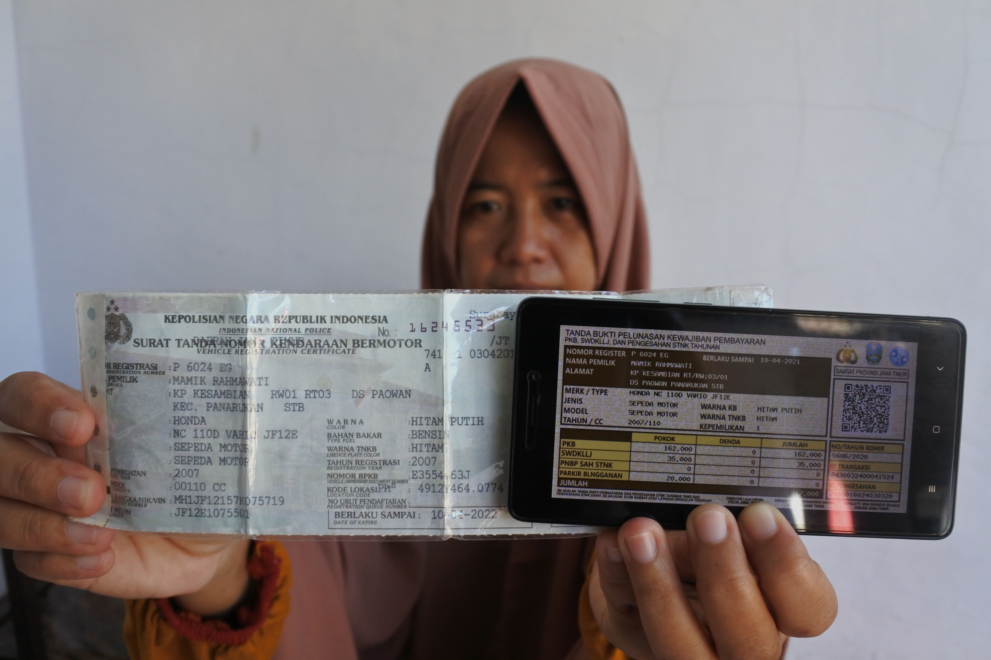 Seorang warga memperlihatkan bukti pelunasan pajak kendaraan bermotor yang dibayar secara daring atau online dari rumah.