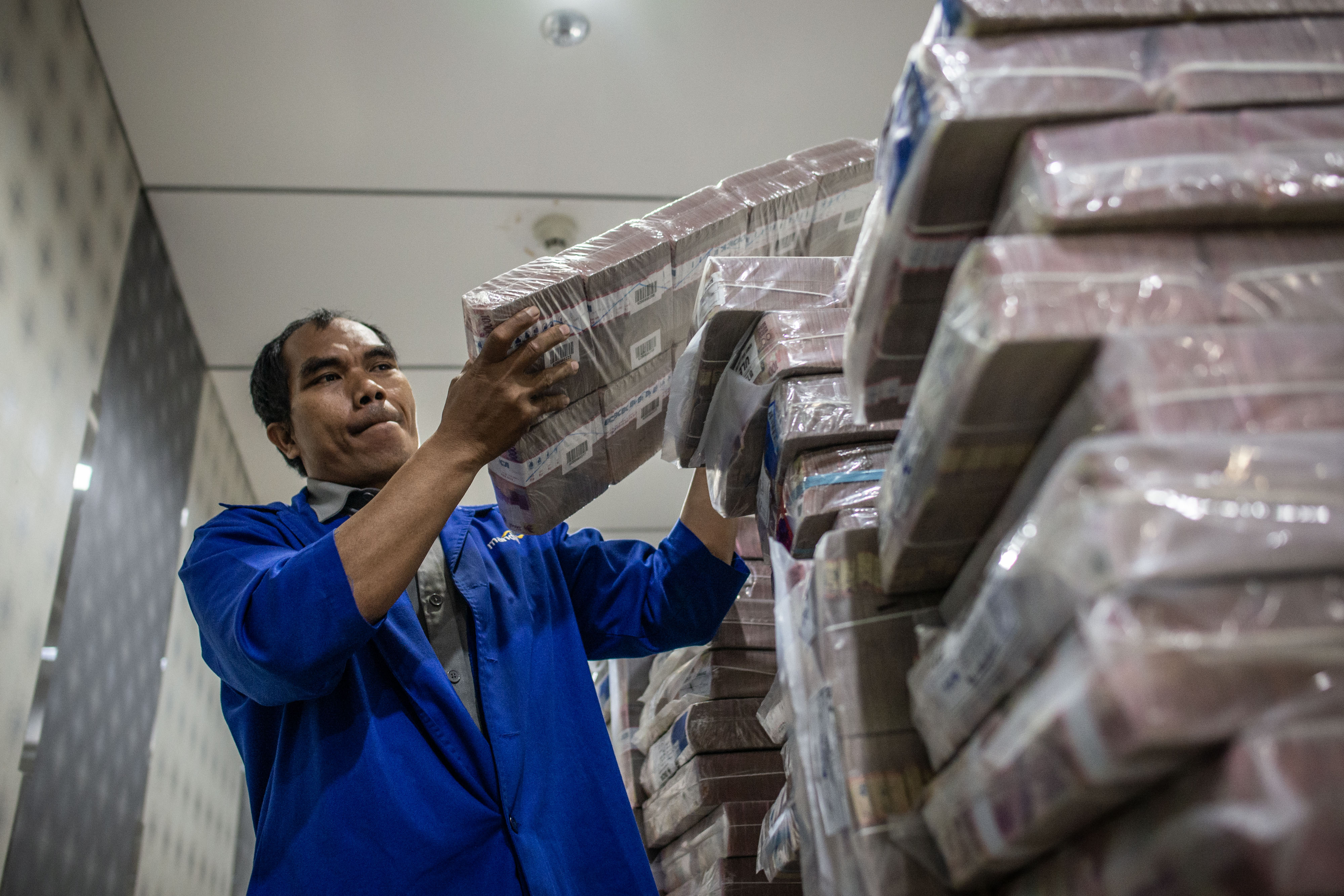 Pegawai sedang menyusun uang yang akan didistribusikan.