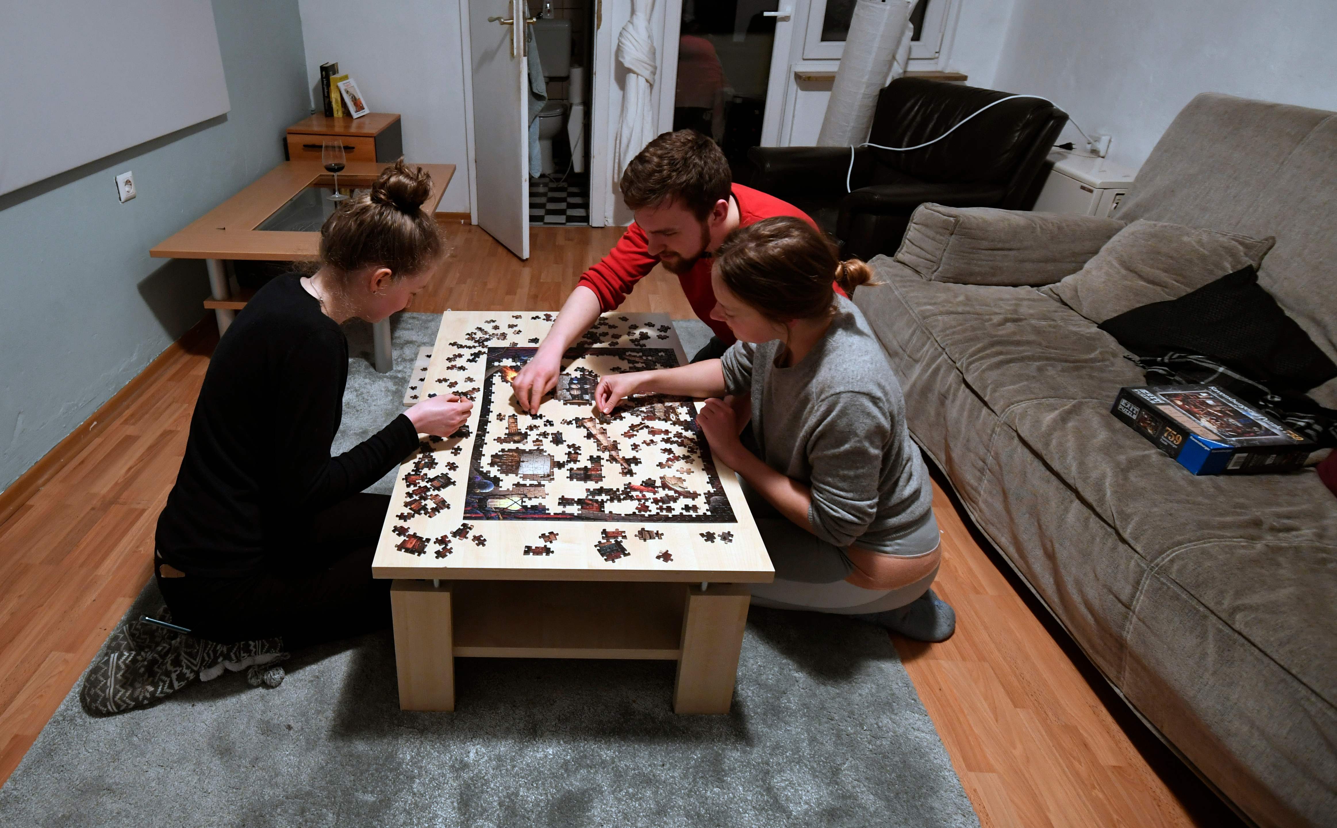 Sebuah keluarga di Jerman bermain puzzle untuk mengisi waktu selama diam di rumah