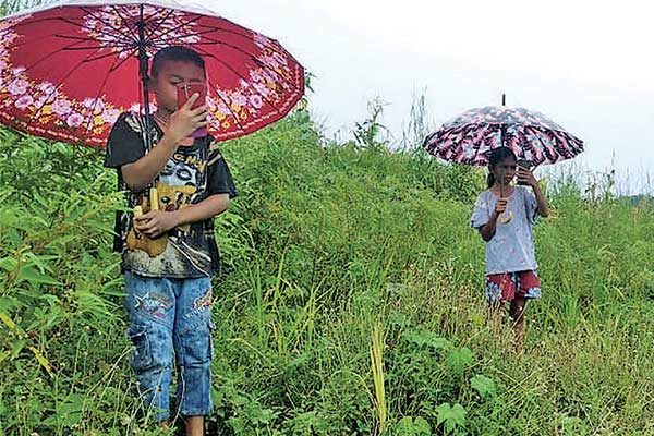 Dua murid SD tengah mencari sinyal internet di perbukitan saat menjalani kegiatan belajar di rumah secara daring di Flores Timur, NTT.