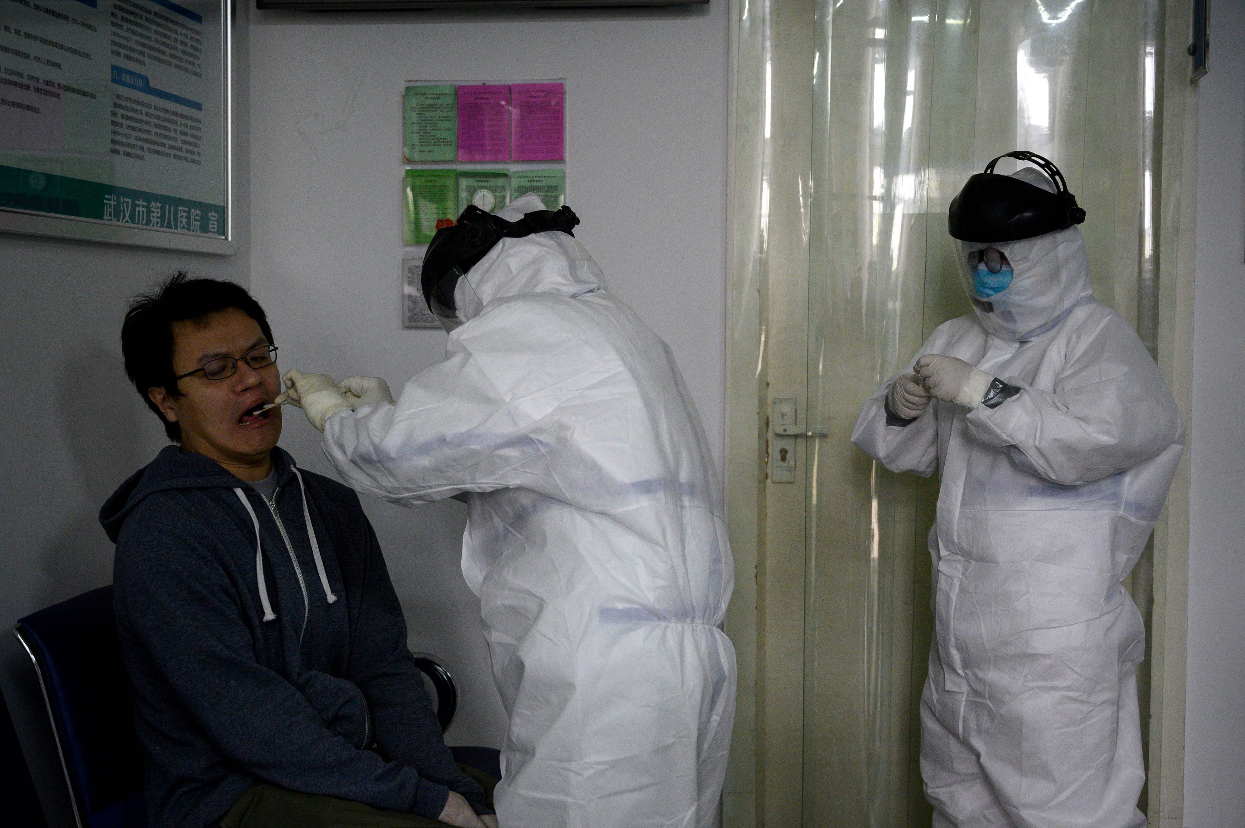 Seorang pekerja medis mengambil sampel swab dari seseorang untuk diuji tes Covid-19 di rumah sakit Wuhan, Hubei pada 10 April 2020.