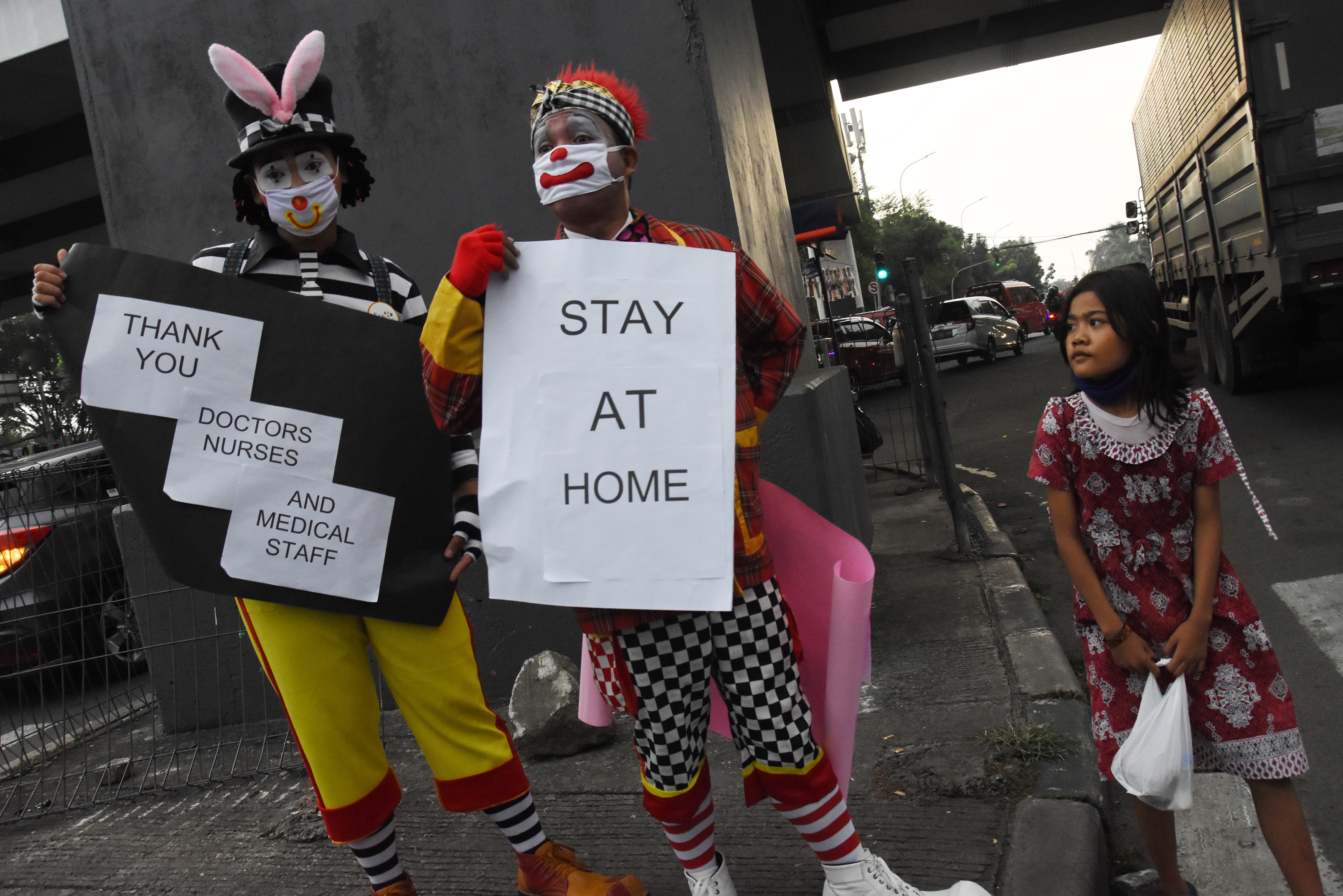 Komunitas Aku Badut Indonesia membawa poster kampanye pencegahan covid-19 di persimpangan Pasar Rebo, Jakarta.