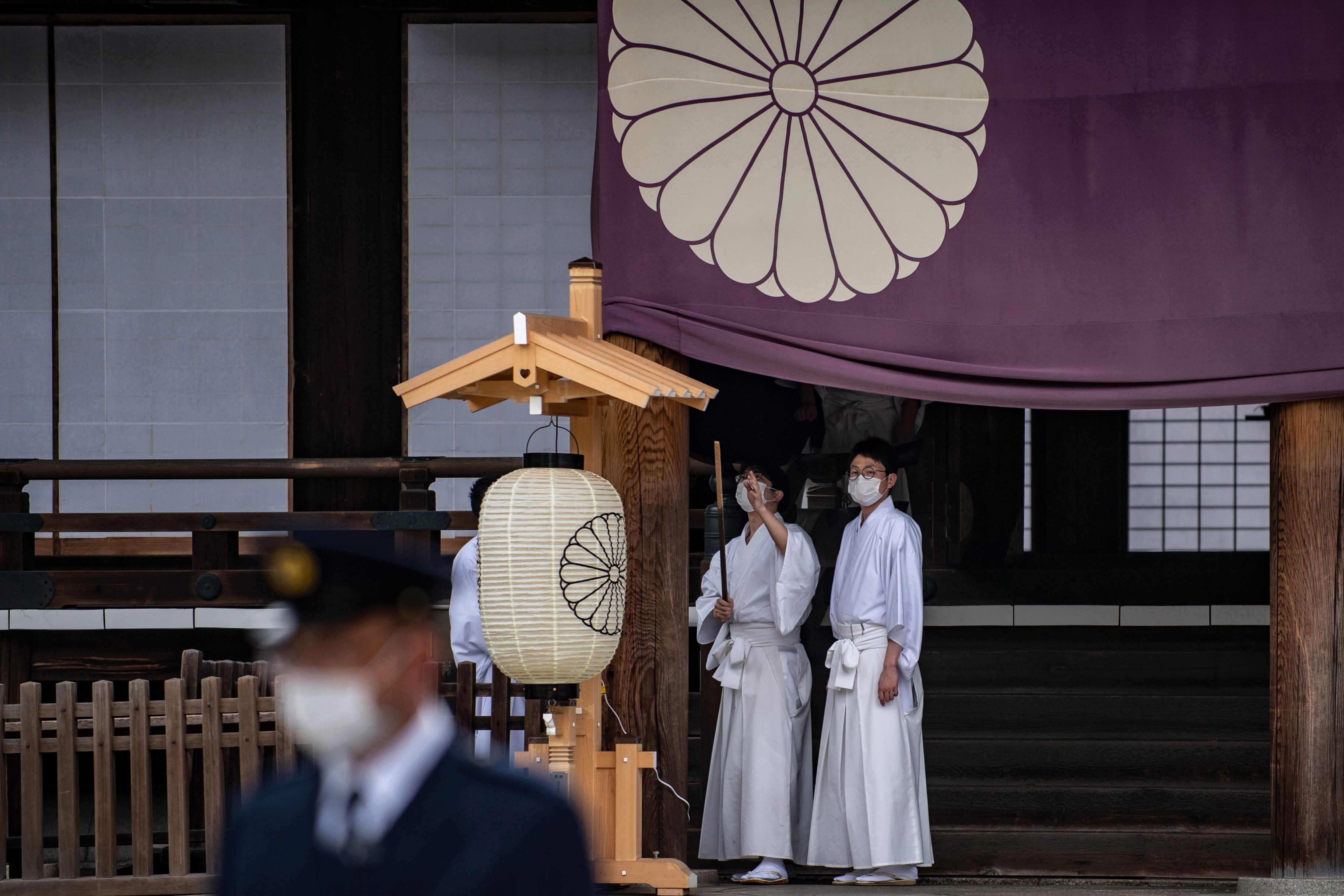 Staf kuil Yasukuni di Tokyo memakai masker saat akan menyiapkan ritual musim semi tahunan pada 21 April