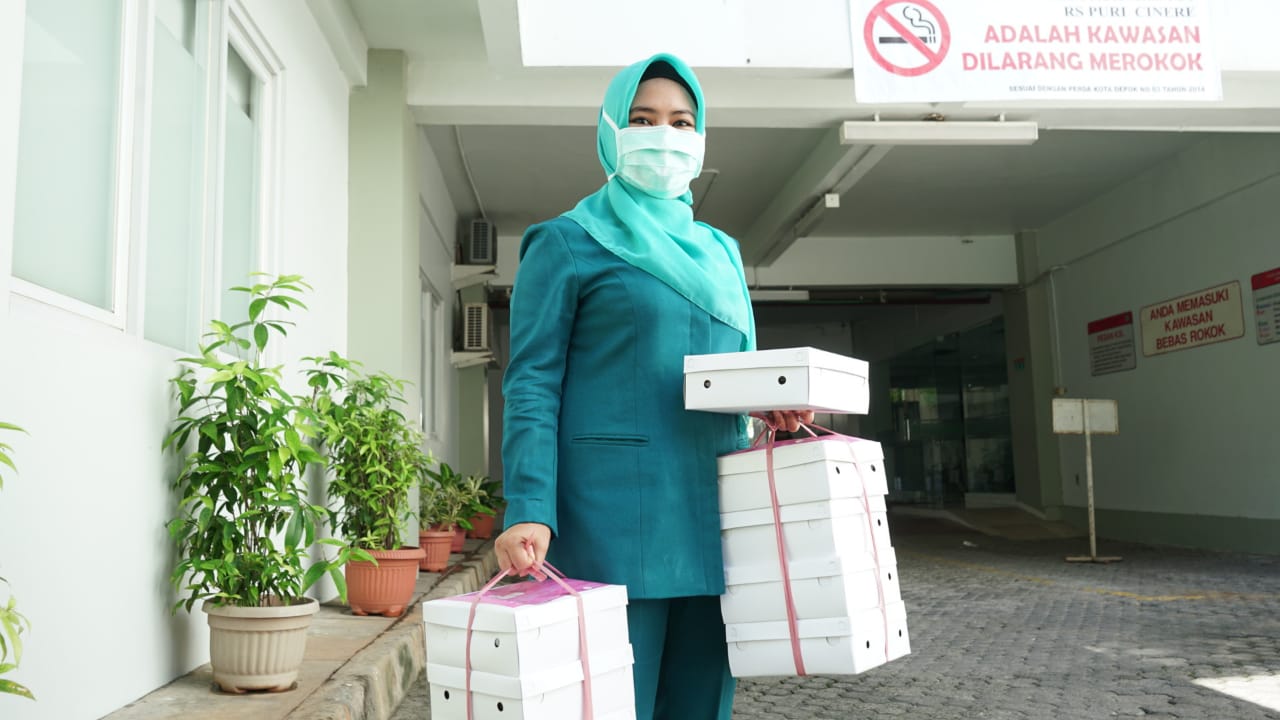 Diana Dewi membawa kotak makanan untuk tenaga media di Depok