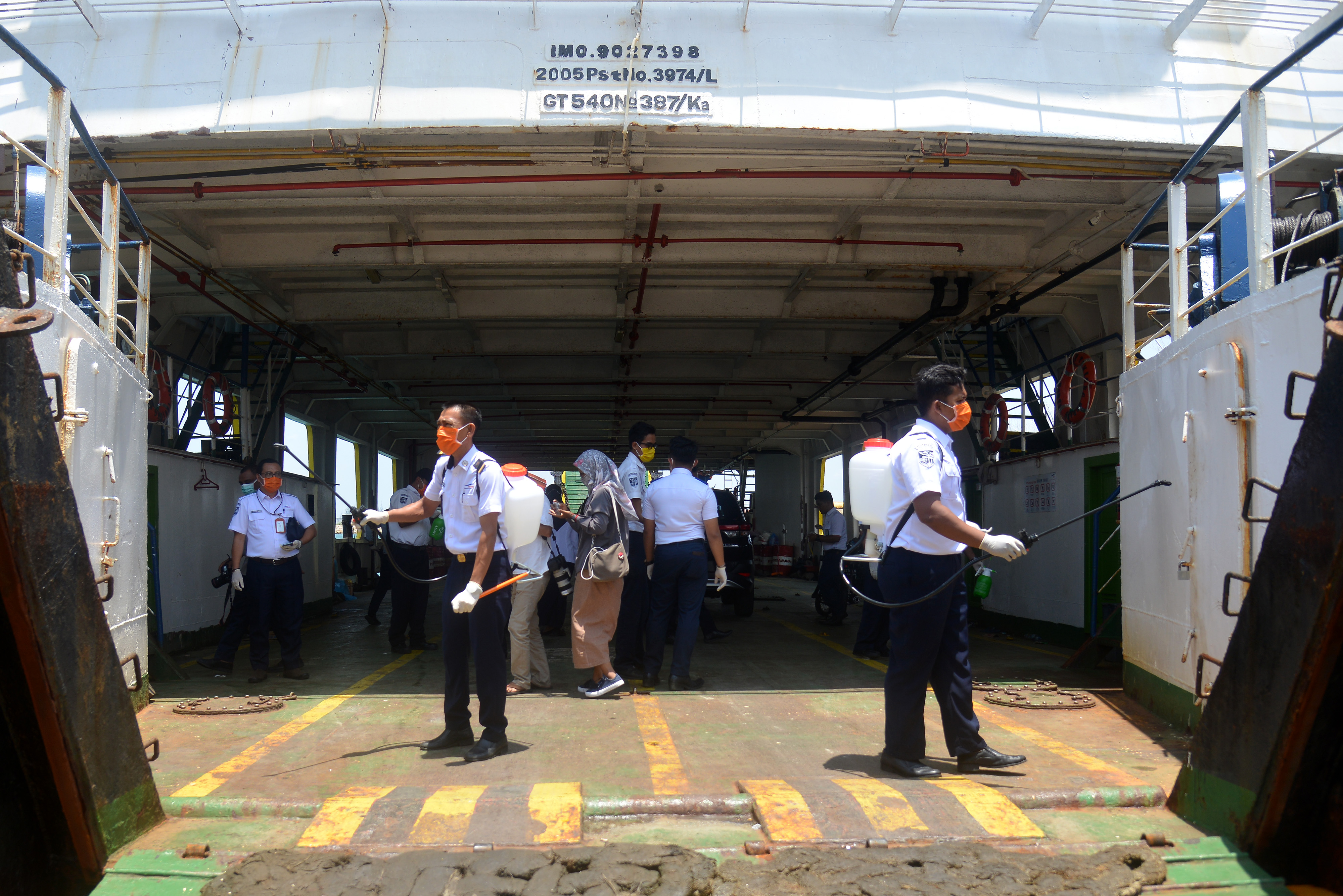 Petugas PT Angkutan Sungai Danau dan Penyeberangan (ASDP) menyemprotkan cairan disinfektan di pintu masuk kapal.