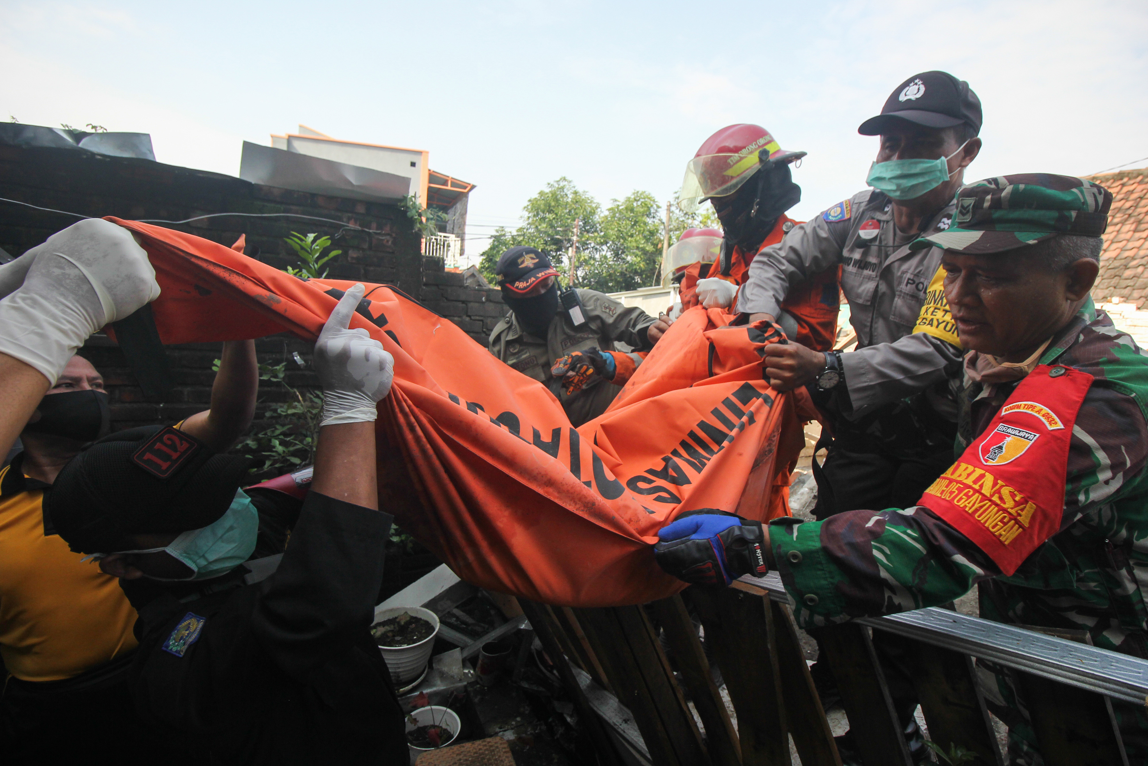 Petugas mengevakuasi jenazah korban yang tertimpa reruntuhan bangunan rumah.