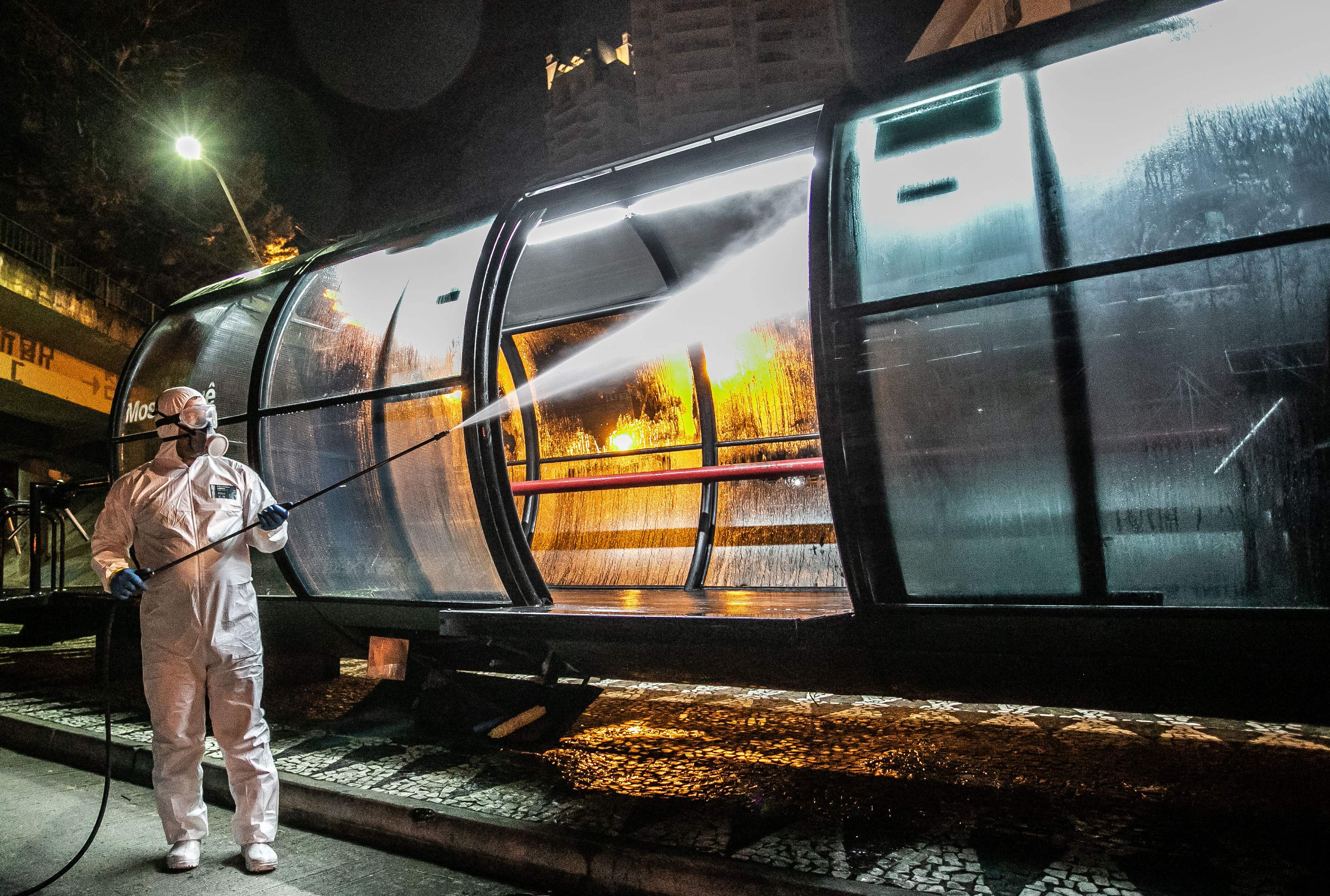 Seorang pekerja menyemprotkan cairan disinfektan di sebuah stasiun bus di Curitiba, Brasil.