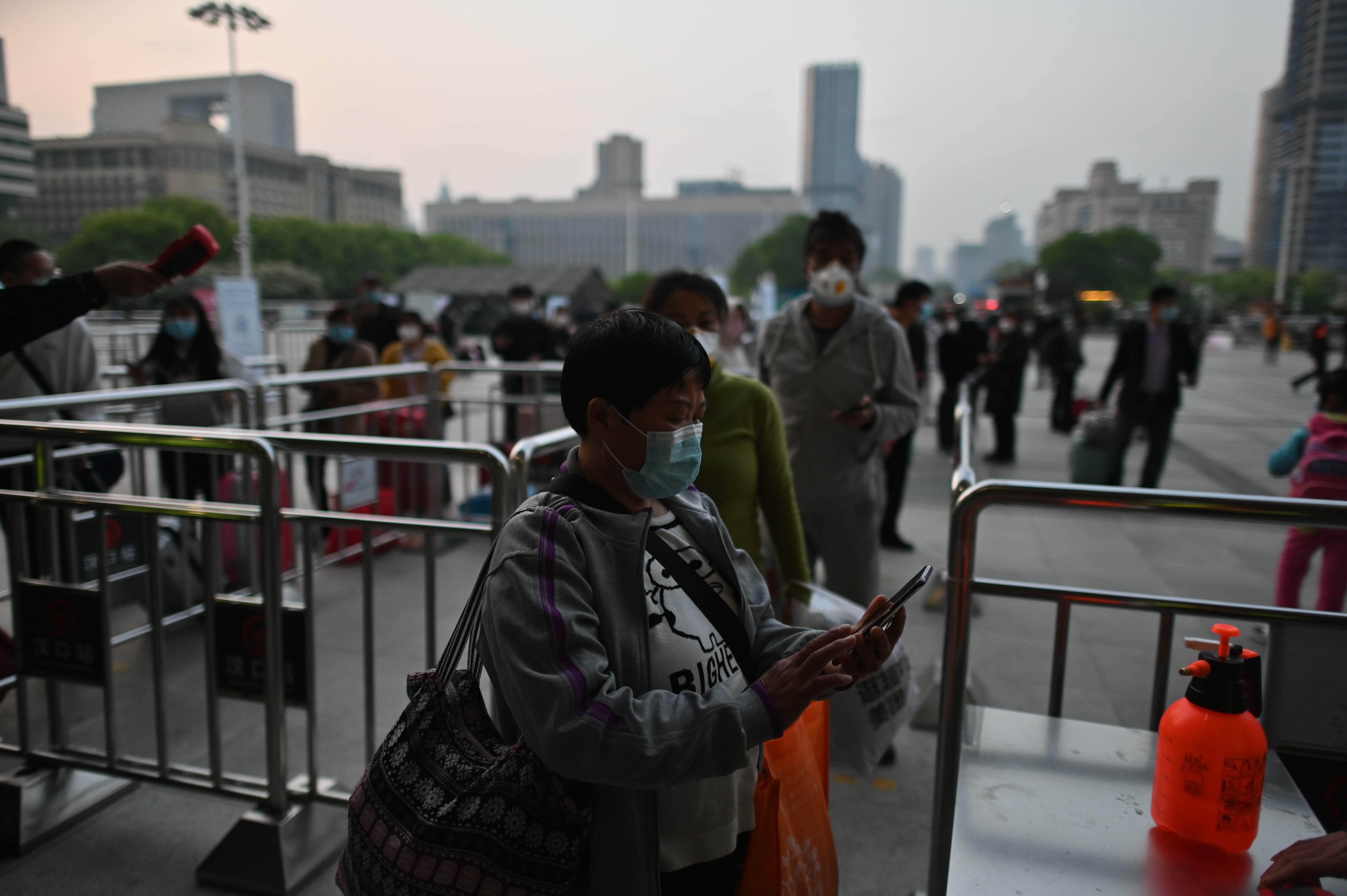Warga Wuhan mengantre untuk menunjukkan kode kesehatan mereka saat akan memasuki stasiun kereta api.