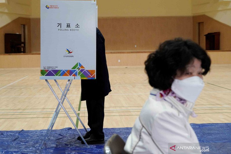 Warga yang memakai masker menunggu untuk memberikan suara dalam pemilu legislatif di tengah pandemi Covid-19.