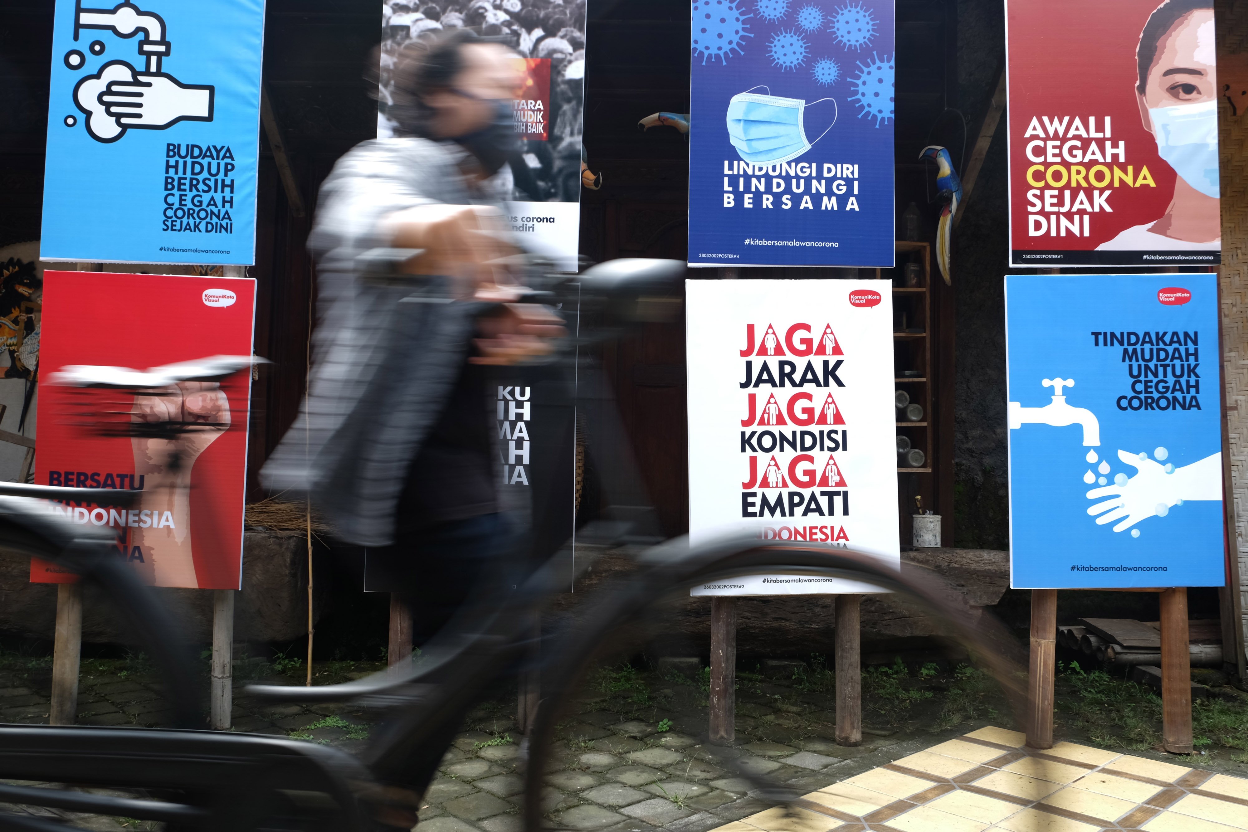 Warga melintasi sejumlah poster terkait upaya melawan covid-19 di Solo, Jawa Tengah.