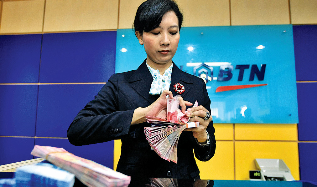 Teller PT Bank Tabungan Negara (Persero) Tbk menghitung uang, di Jakarta.