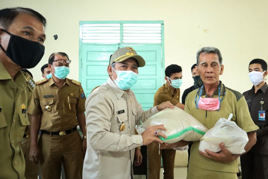 Bupati OKI Iskandar (kiri) membagikan 60.000 paket sembako kepada masyarakat yang terdampak pandemi virus korona di OKI.