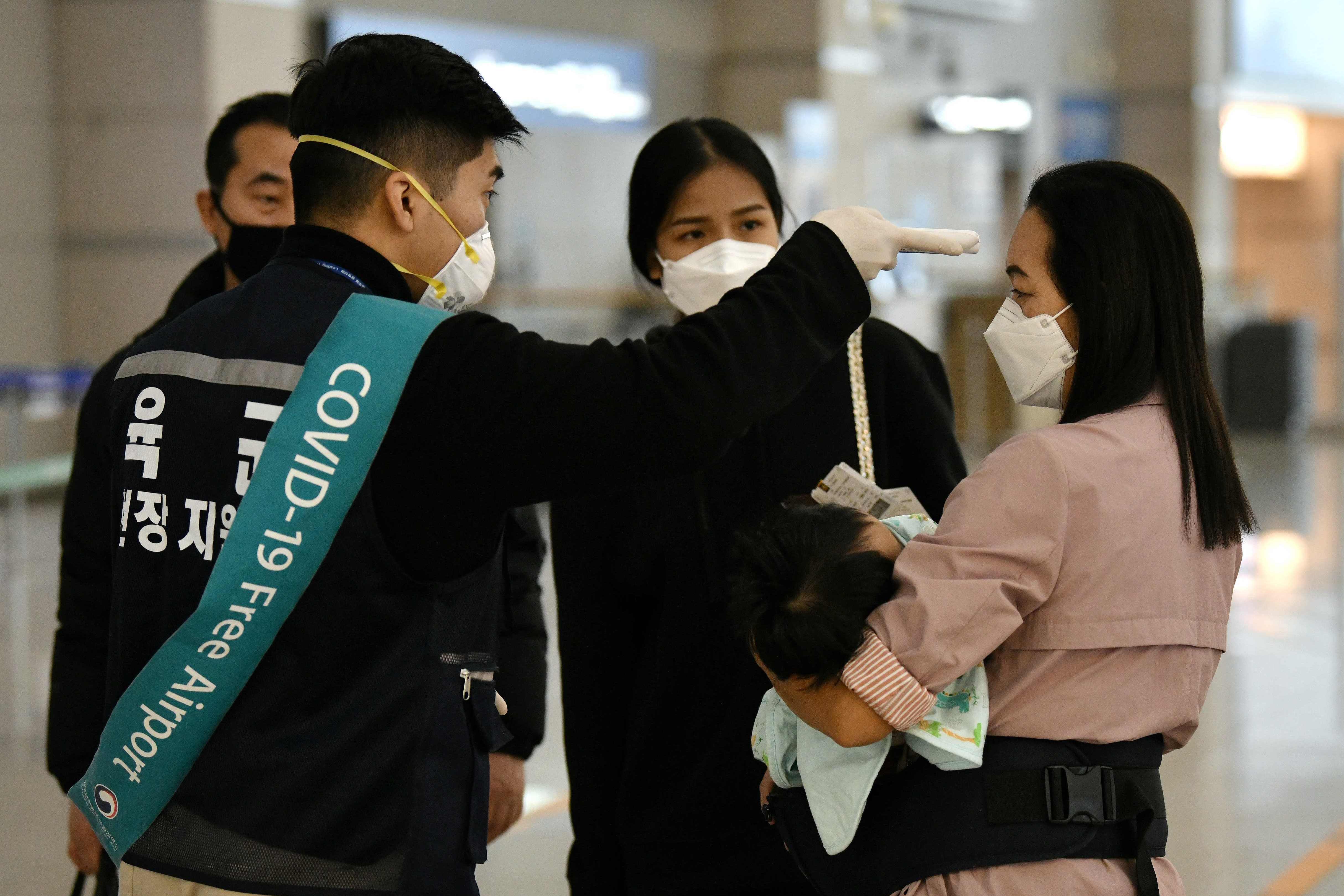 Petugas memeriksa suhu tubuh penumpang di Bandara Incheon, Seoul, Korea Selatan.