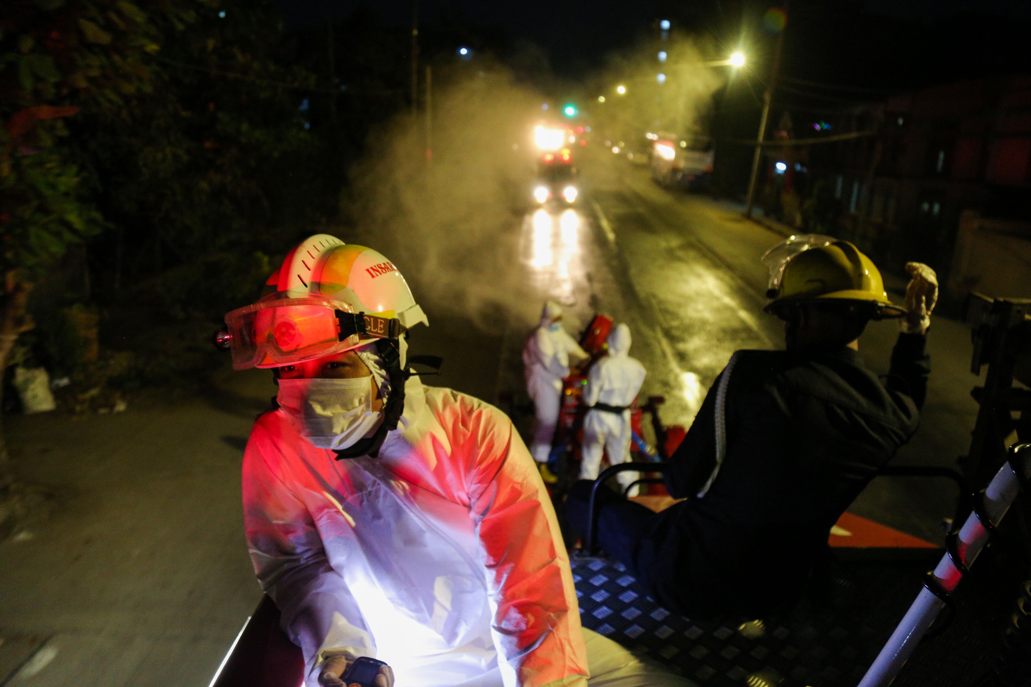 Petugas pemadam kebakaran menyemprot disinfektan di sepanjang jalan sebagai tindakan pencegahan terhadap penyebaran covid-19 di Yangoon.