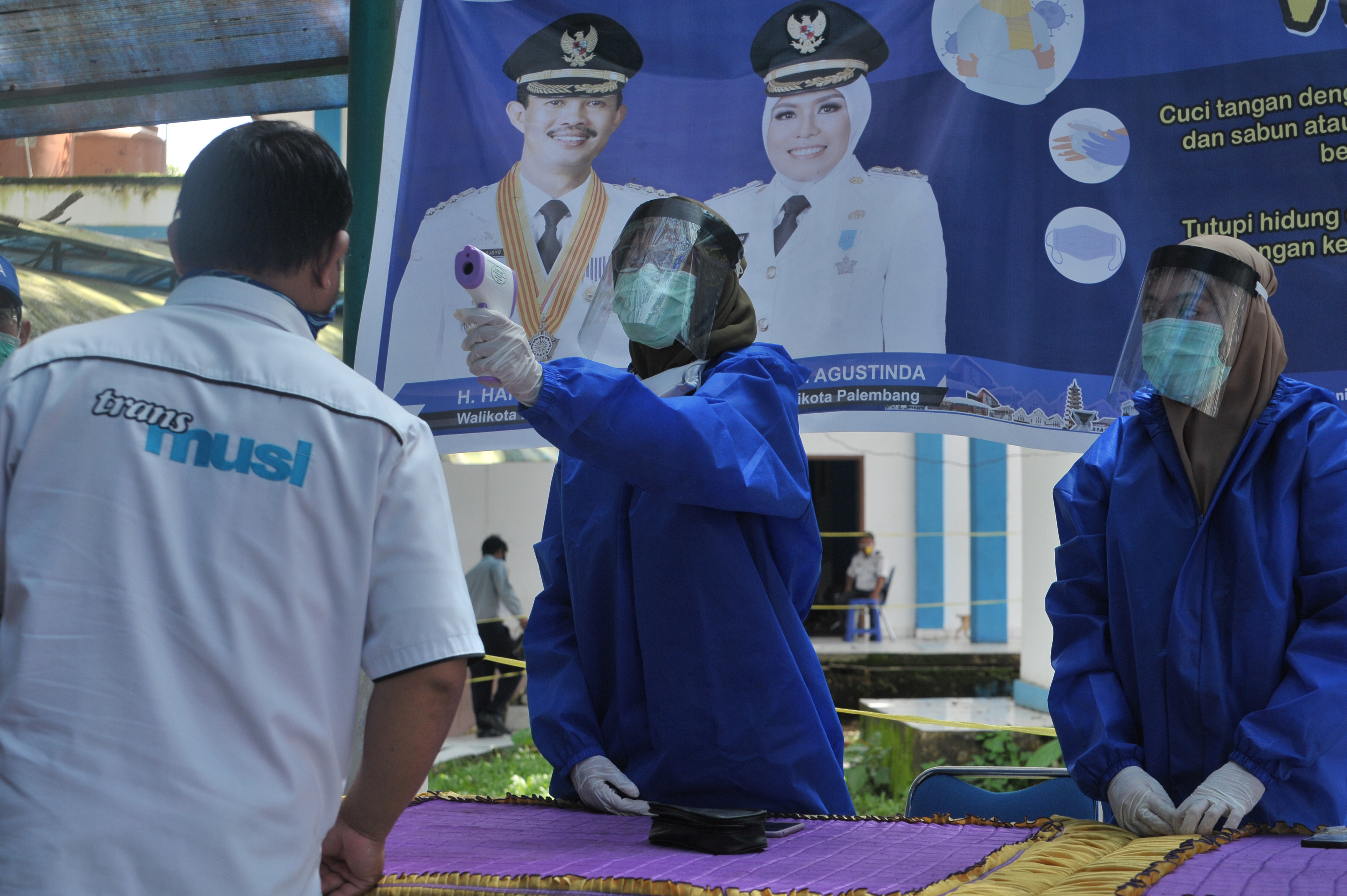 Petugas memeriksa suhu salah satu penumpang yang turun di terminal Alang Alang Lebar Palembang,Sumsel, Senin (20/4). 