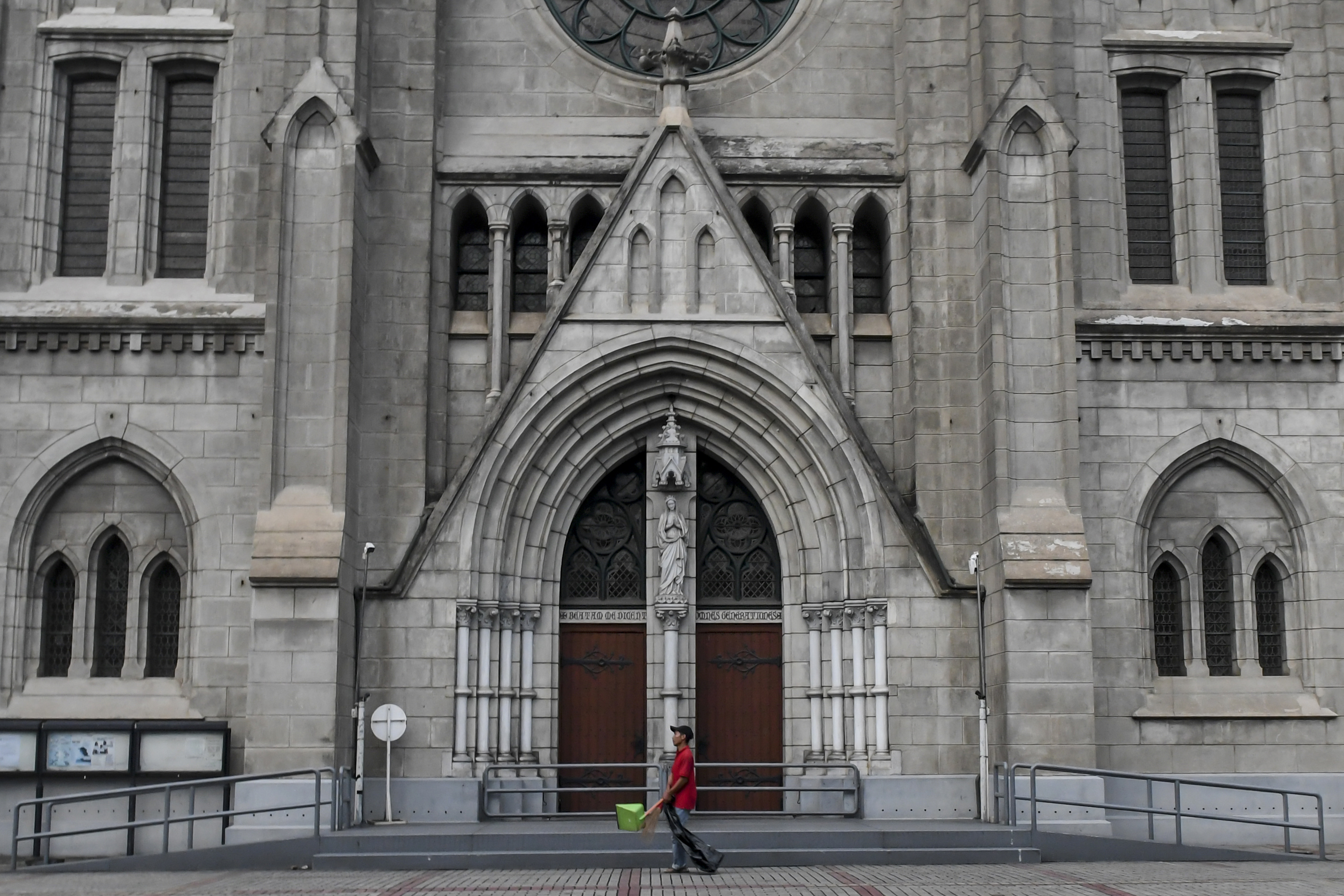 Petugas kebersihan melintas di depan pintu Gereja Katedral, Jakarta, Minggu (5/4). 