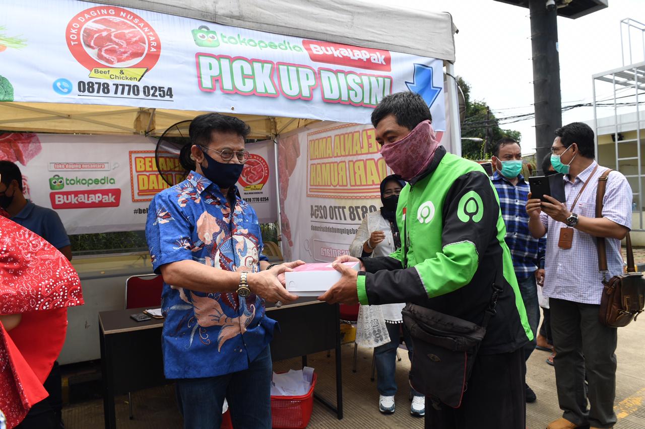 Mentan Syahrul Yasin Limpo memberikan barang secara simbolis pada pengemudi ojek online saat peluncuran Pasar Mitra Tani di Bekasi. 