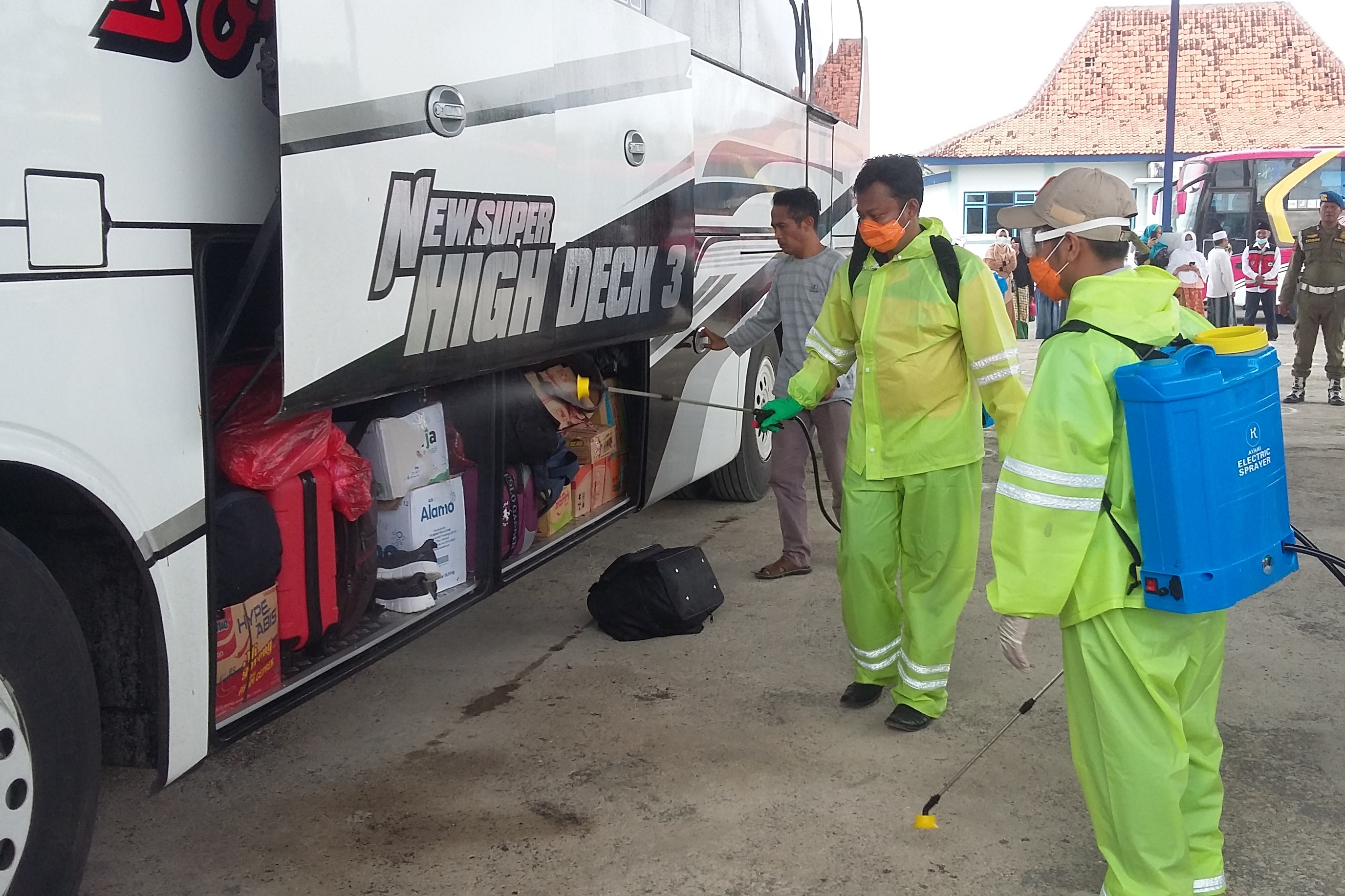 Petugas menyemprotkan cairan disinfektan ke barang pemudik di Terminal Ronggosukowati Pamekasan, Jawa Timur.