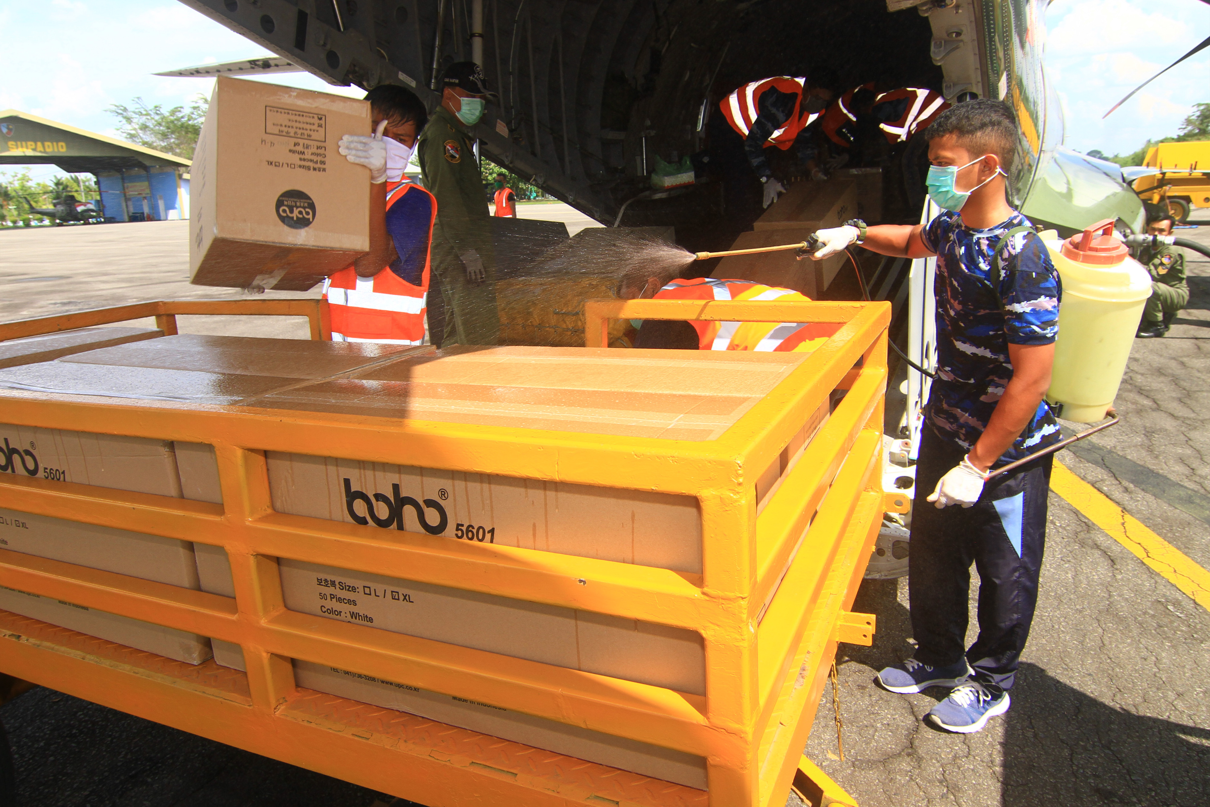 Anggota TNI AU mengangkat kardus berisi Alat Pelindung Diri (APD) dari pesawat Hercules CN-295 di Lanud Supadio, Kalimantan Barat. 