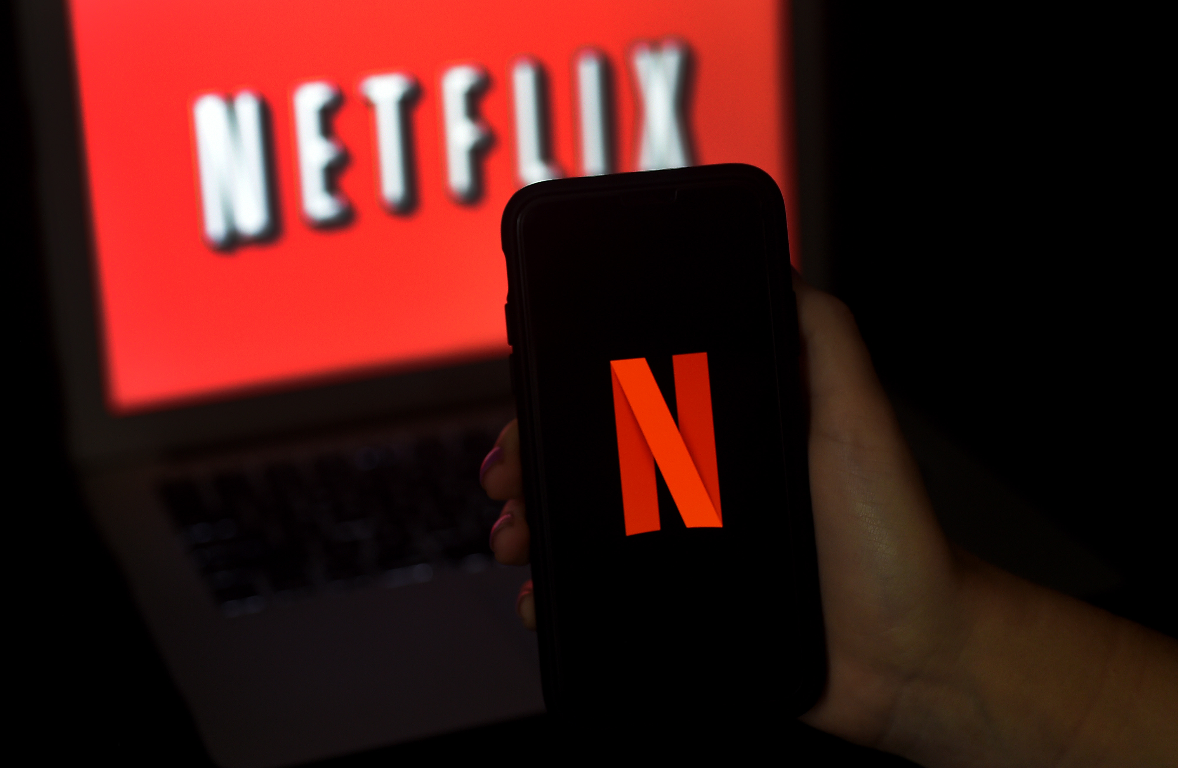 Logo Netflix terlihat di layar komputer dan ponsel.