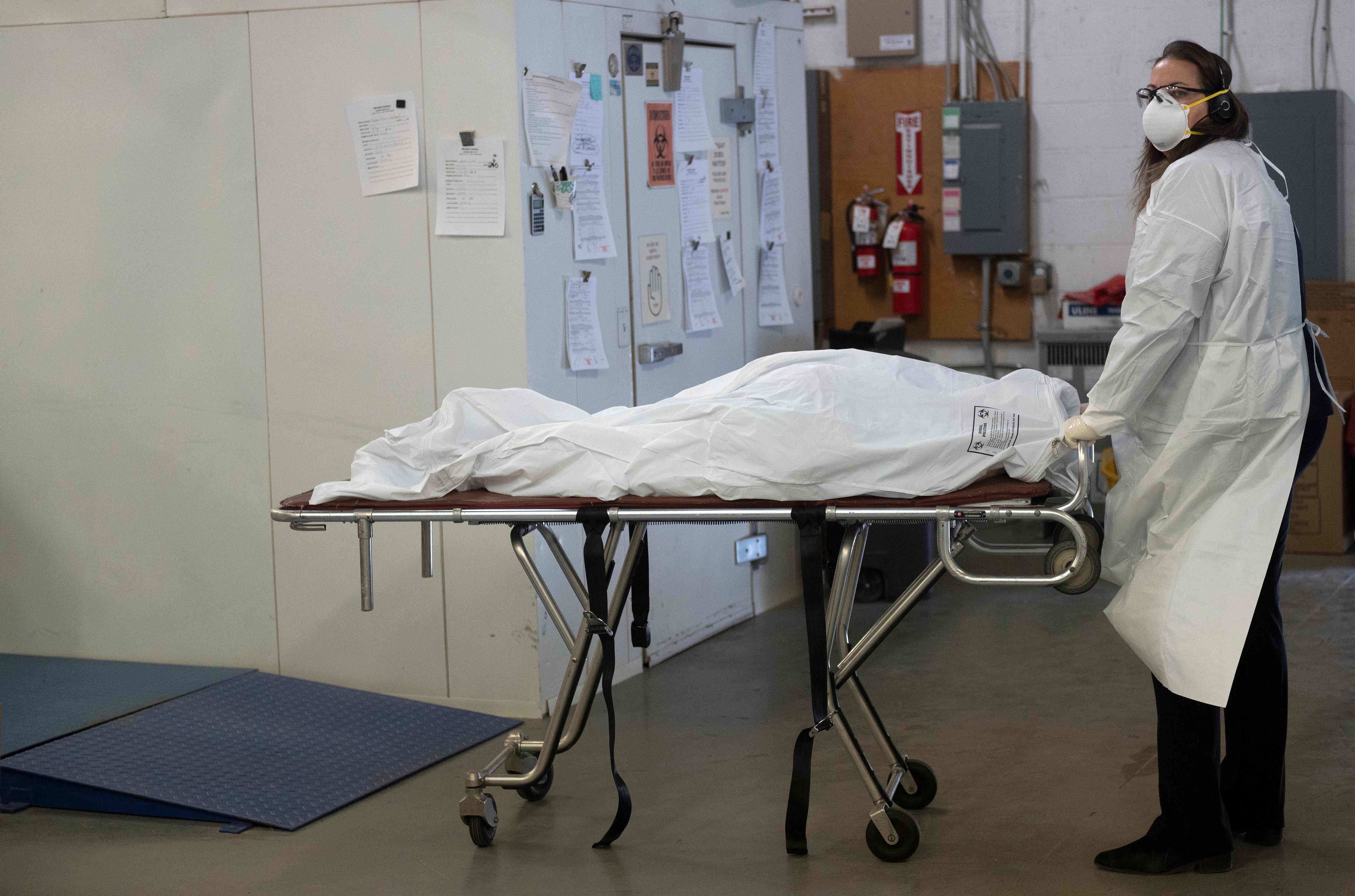 Petugas mendorong jenazah korban covid-19 yang akan dikremasi di New York, Amerika Serikat.