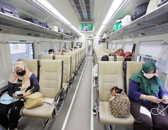 Penumpang duduk dengan menjaga jarak (physical distancing) di dalam gerbong kereta.