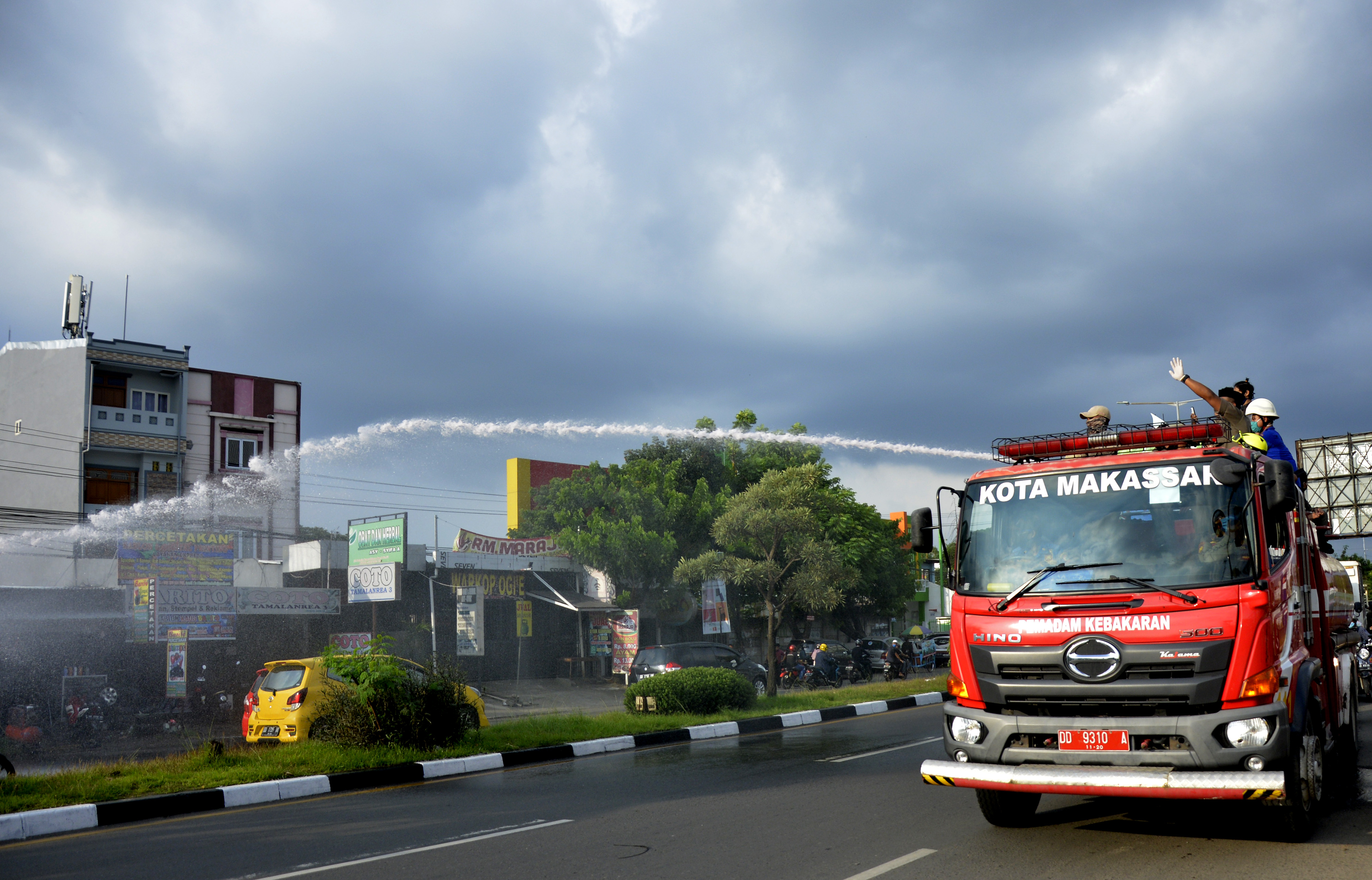 Petugas menyemprotkan air ke arah toko yang masih beroperasi di Makassar, Sulawesi Selatan, Rabu (29/4). 