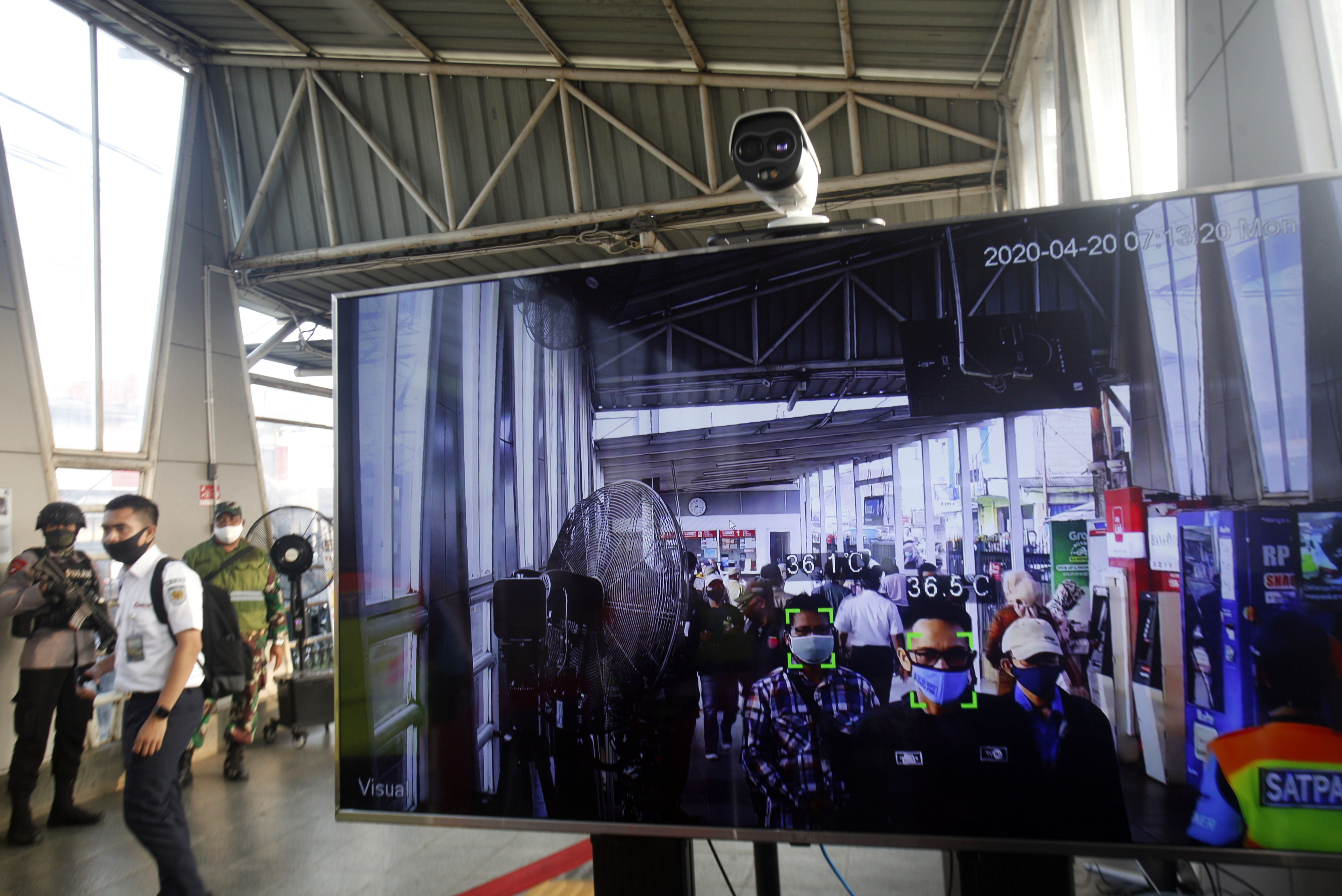 Penumpang melintasi alat pendeteksi suhu tubuh (thermal scanner) di Stasiun Bojonggede, Bogor, Jawa Barat.