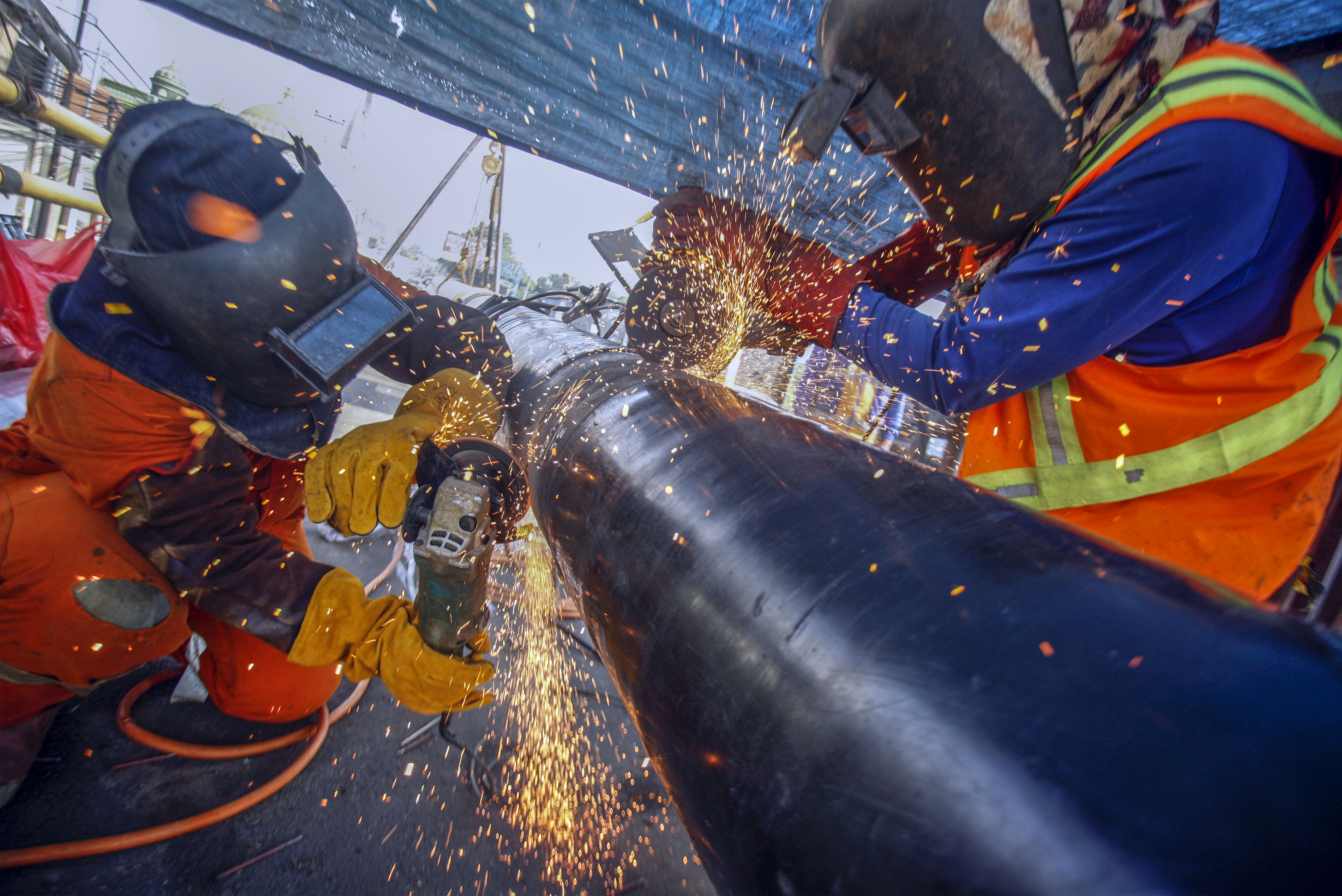 Pekerja menyelesaikan pemasangan pipa jaringan gas.